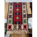 A RED AND CREAM PATTERNED FRINGED RUG