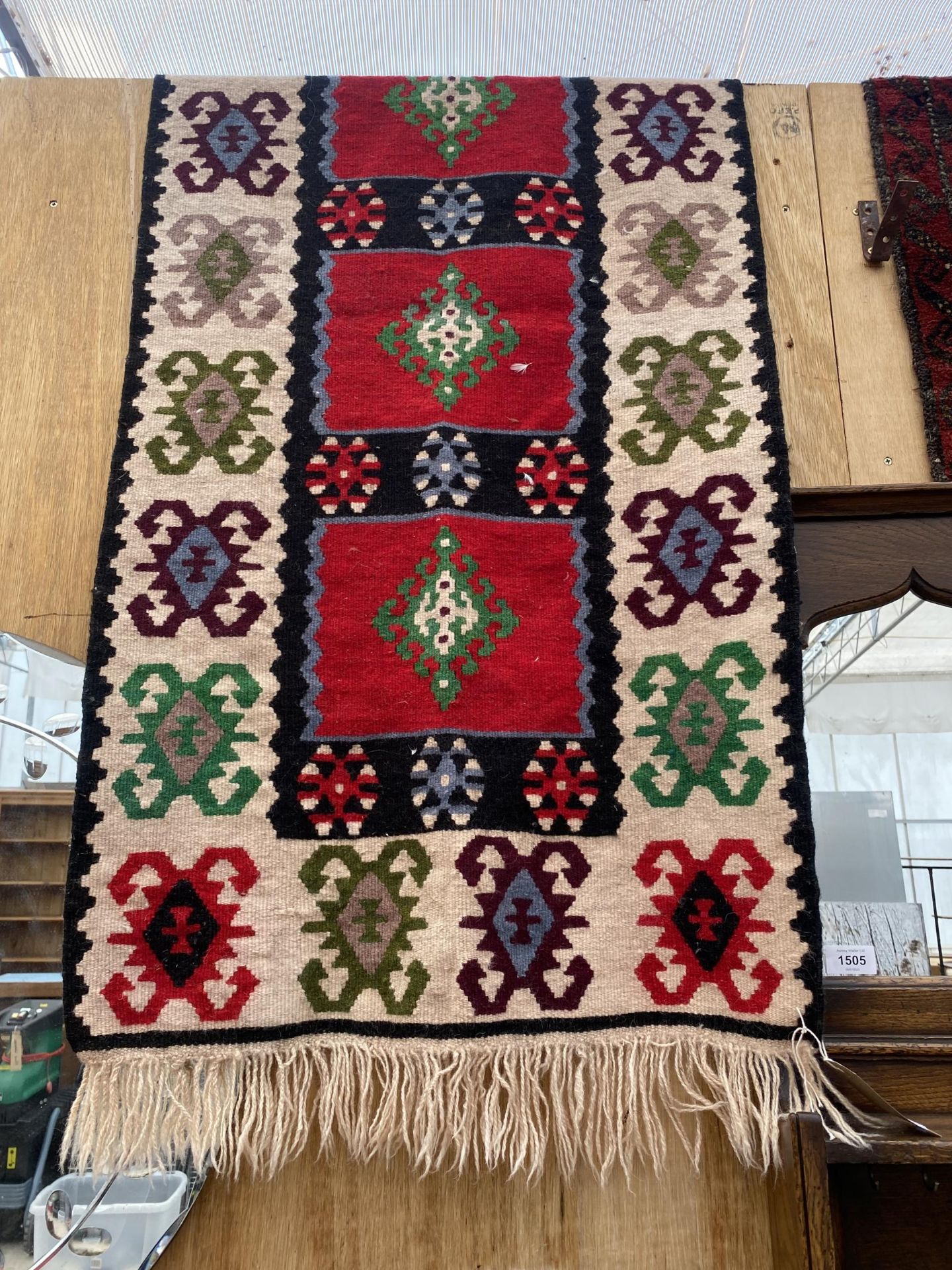 A RED AND CREAM PATTERNED FRINGED RUG