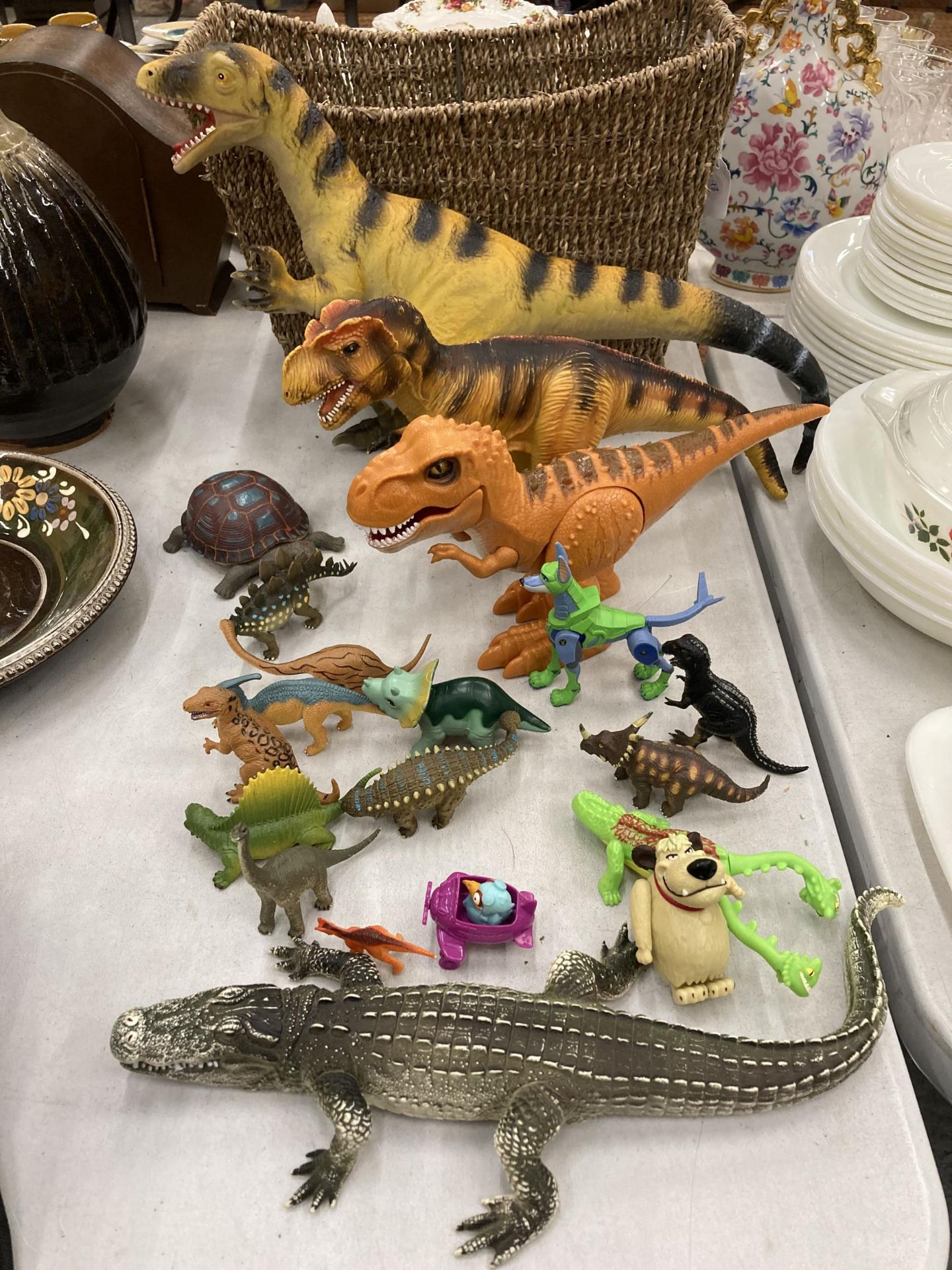 A COLLECTION OF DINOSAURS, ETC IN A BASKET