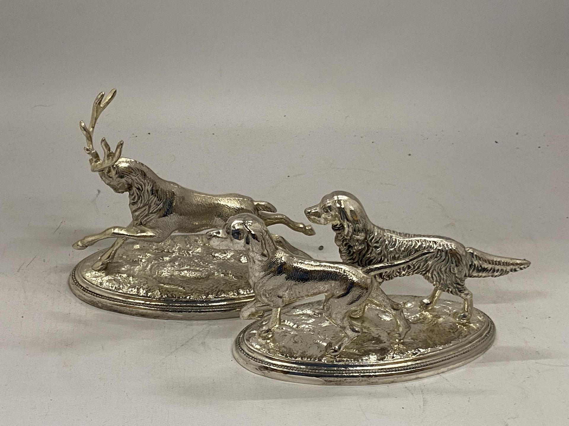 TWO WHITE METAL ORNAMENTS OF A STAG AND TWO HUNTING DOGS