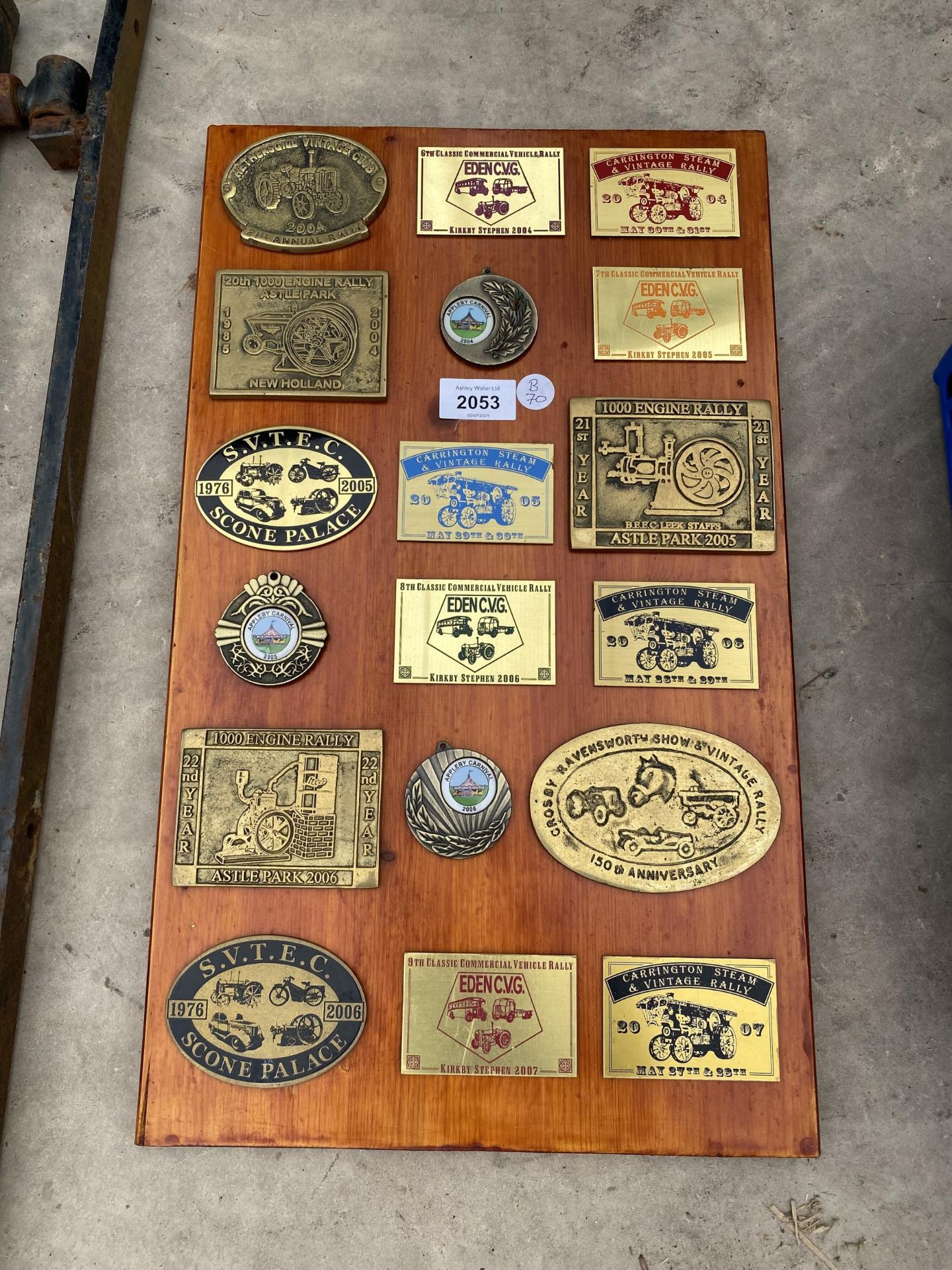 A WOODEN PLAQUE WITH VARIOUS BRASS STEAM RALLY PLAQUES ATTATCHED