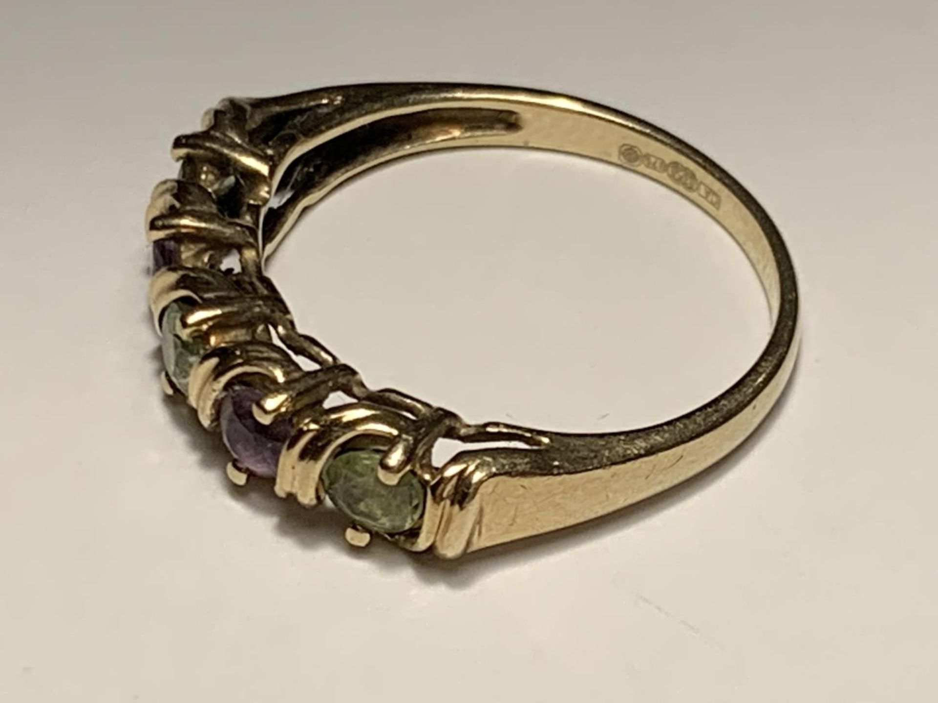 A 9 CARAT GOLD RING WITH TWO AMETHYSTS AND THREE PERIDOTS ON A TWIST DESIGN SIZE M - Image 2 of 4