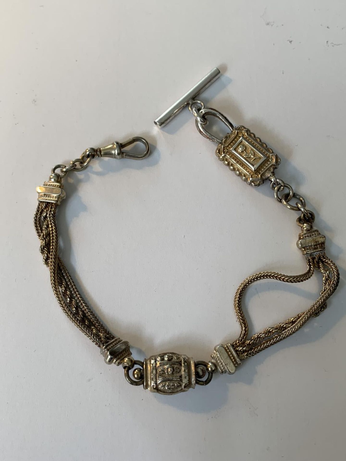 AN ORNATE WHITE METAL HALF ALBERT CHAIN WITH T BAR