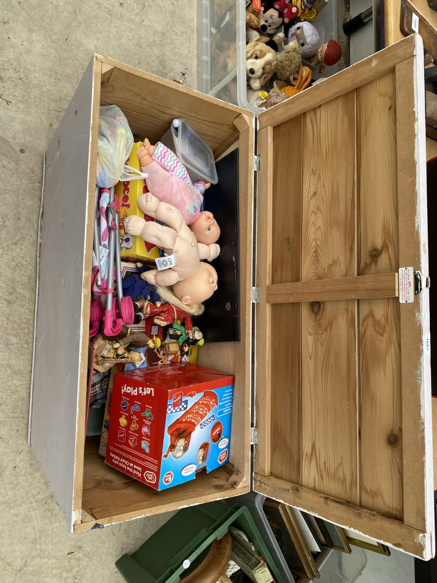 A WOODEN TOY BOX CONTAINING AN ASSORTMENT OF TOYS TO INCLUDE DOLLS AND BOARD GAMES ETC