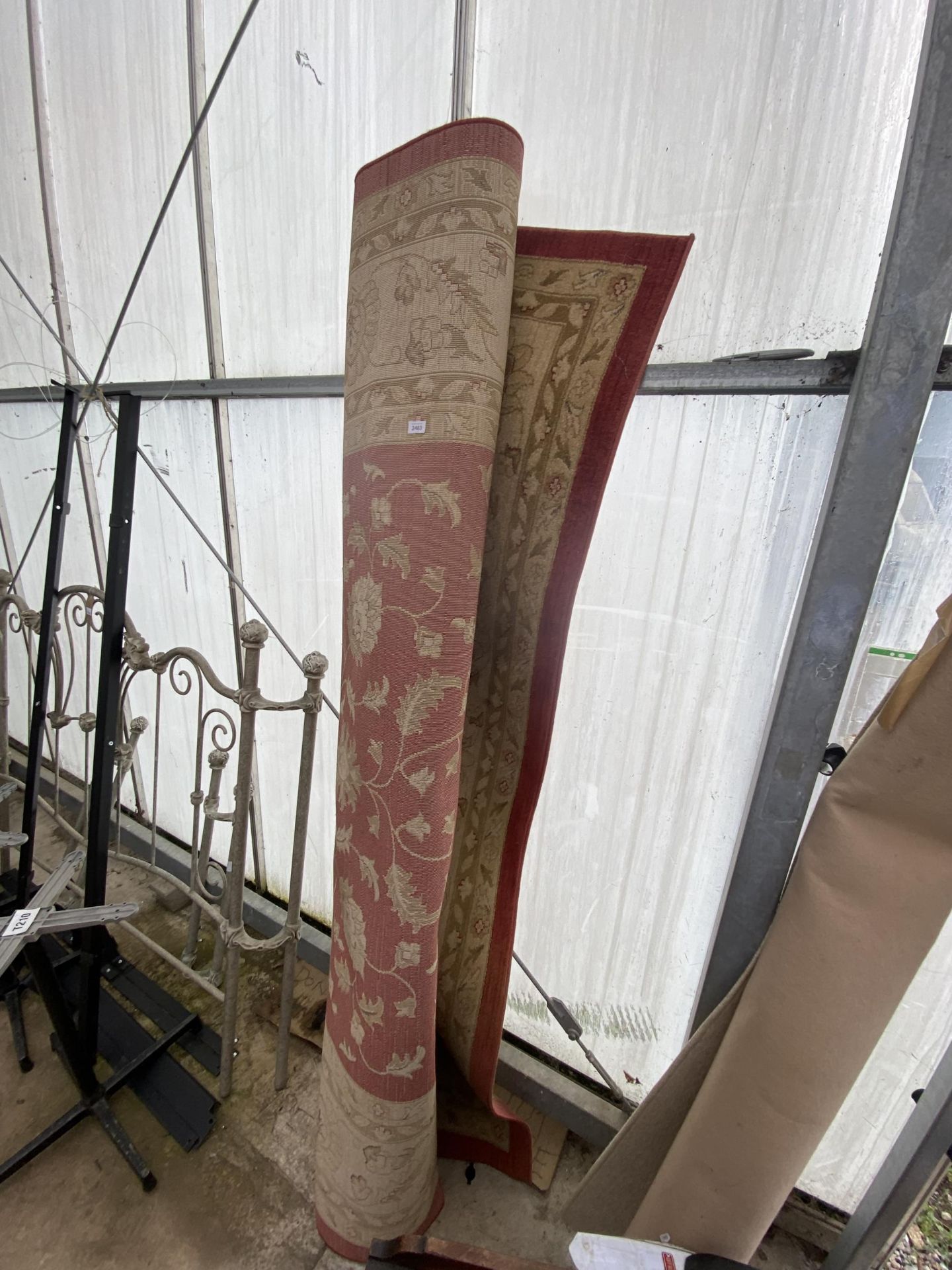 A LARGE RED AND CREAM PATTERNED RUG