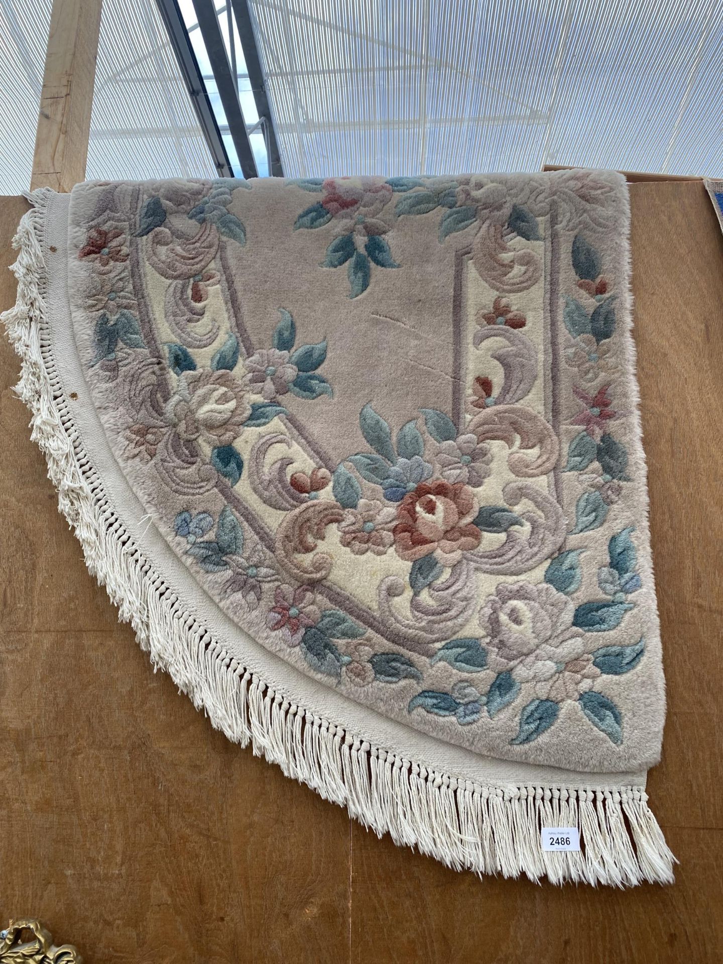 A CREAM HALF MOON FRINGED RUG