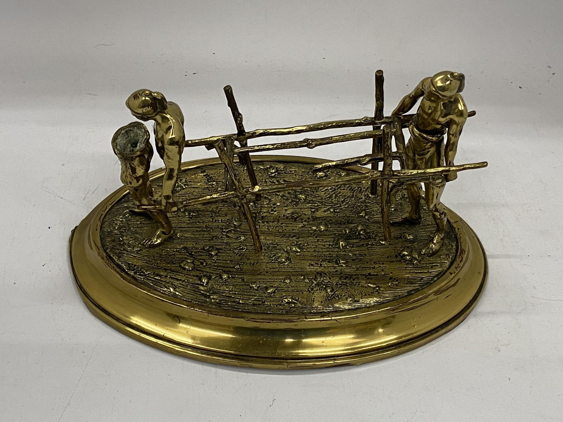 TWO BRASS FIGURES CARRYING A STRETCHER ON A BRASS BASE