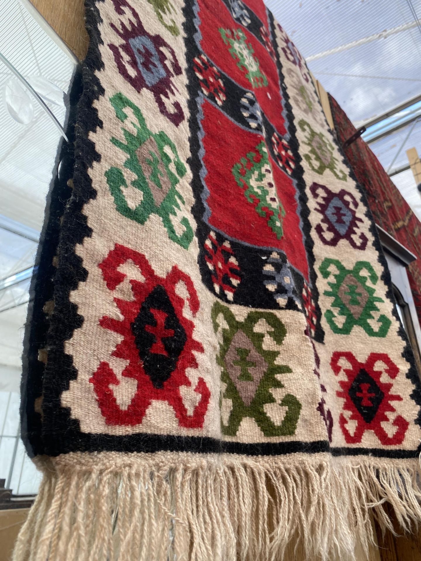 A RED AND CREAM PATTERNED FRINGED RUG - Image 2 of 3