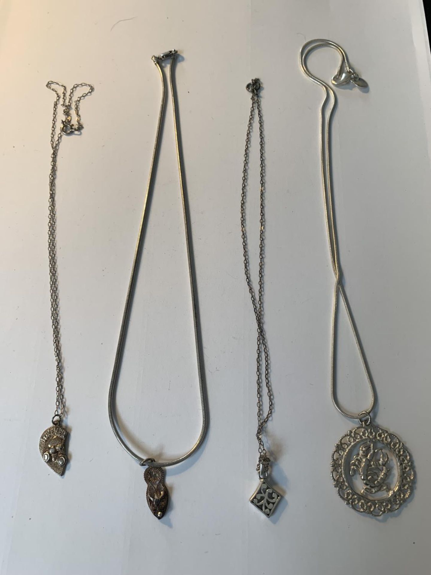 FOUR SILVER NECKLACES WITH PENDANTS