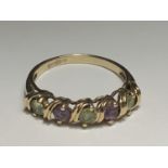 A 9 CARAT GOLD RING WITH TWO AMETHYSTS AND THREE PERIDOTS ON A TWIST DESIGN SIZE M