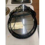 A BLACK GLASS MIRROR WITH AN ORNATE TOP