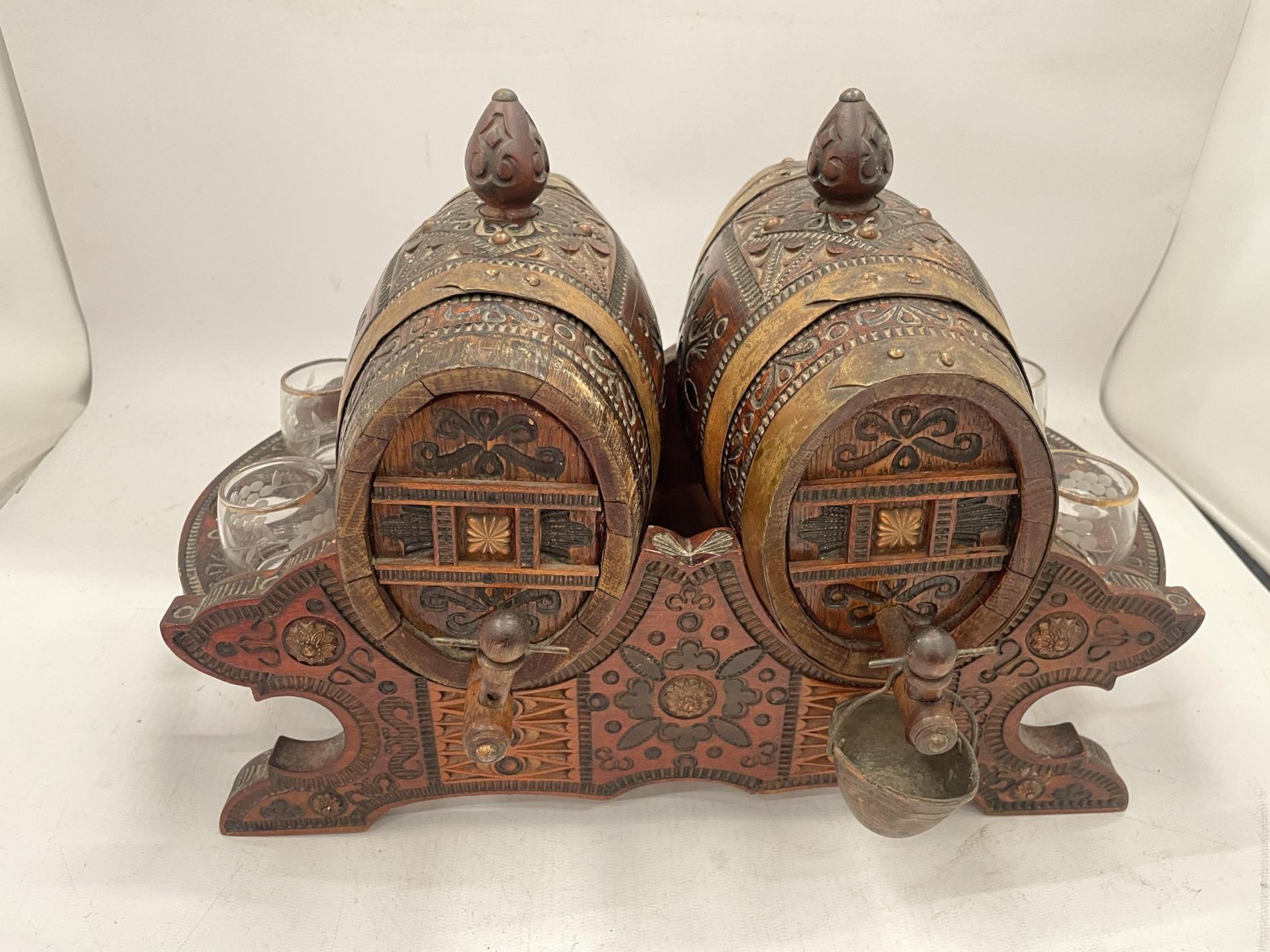 A VINTAGE CARVED WOODEN NORTH AFRICAN DRINKS DISPENSER WITH GLASSES