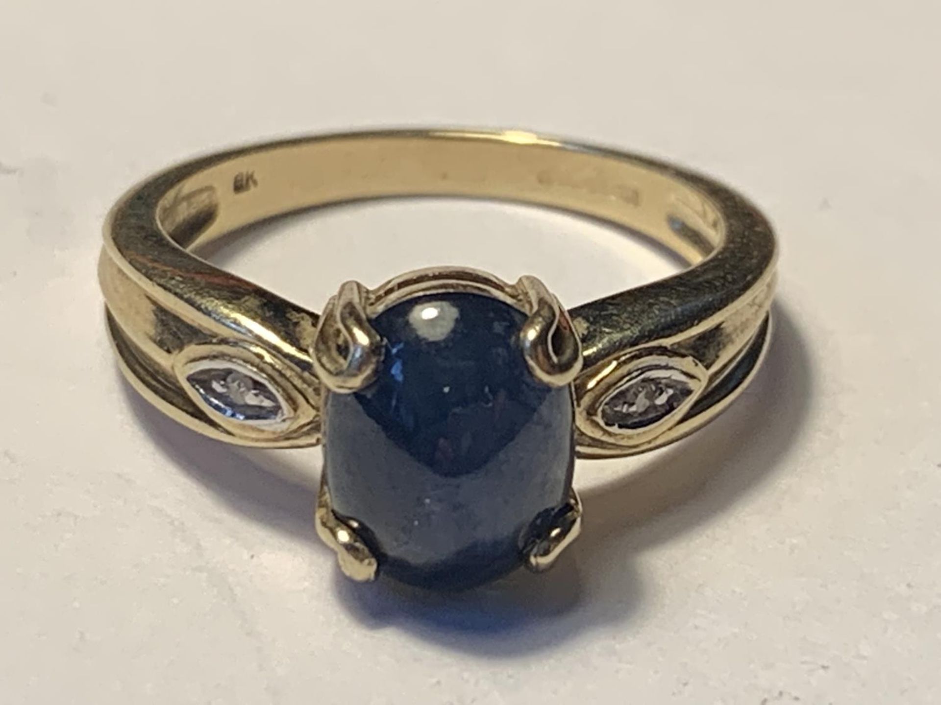 A 9 CARAT GOLD RING WITH A LARGE CENTRE SAPPHIRE AND DIAMONDS TO THE SHOULDERS SIZE N/O