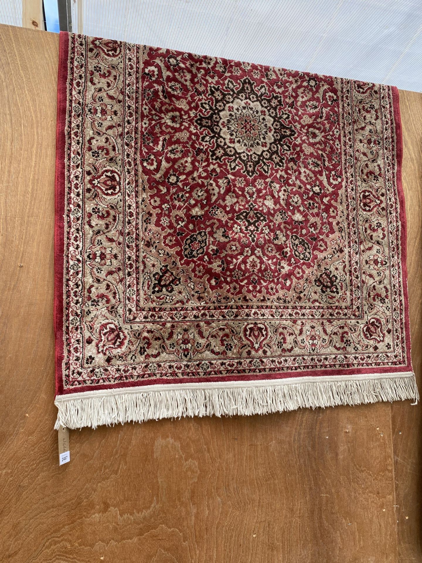 A RED PATTERNED FRINGED RUG