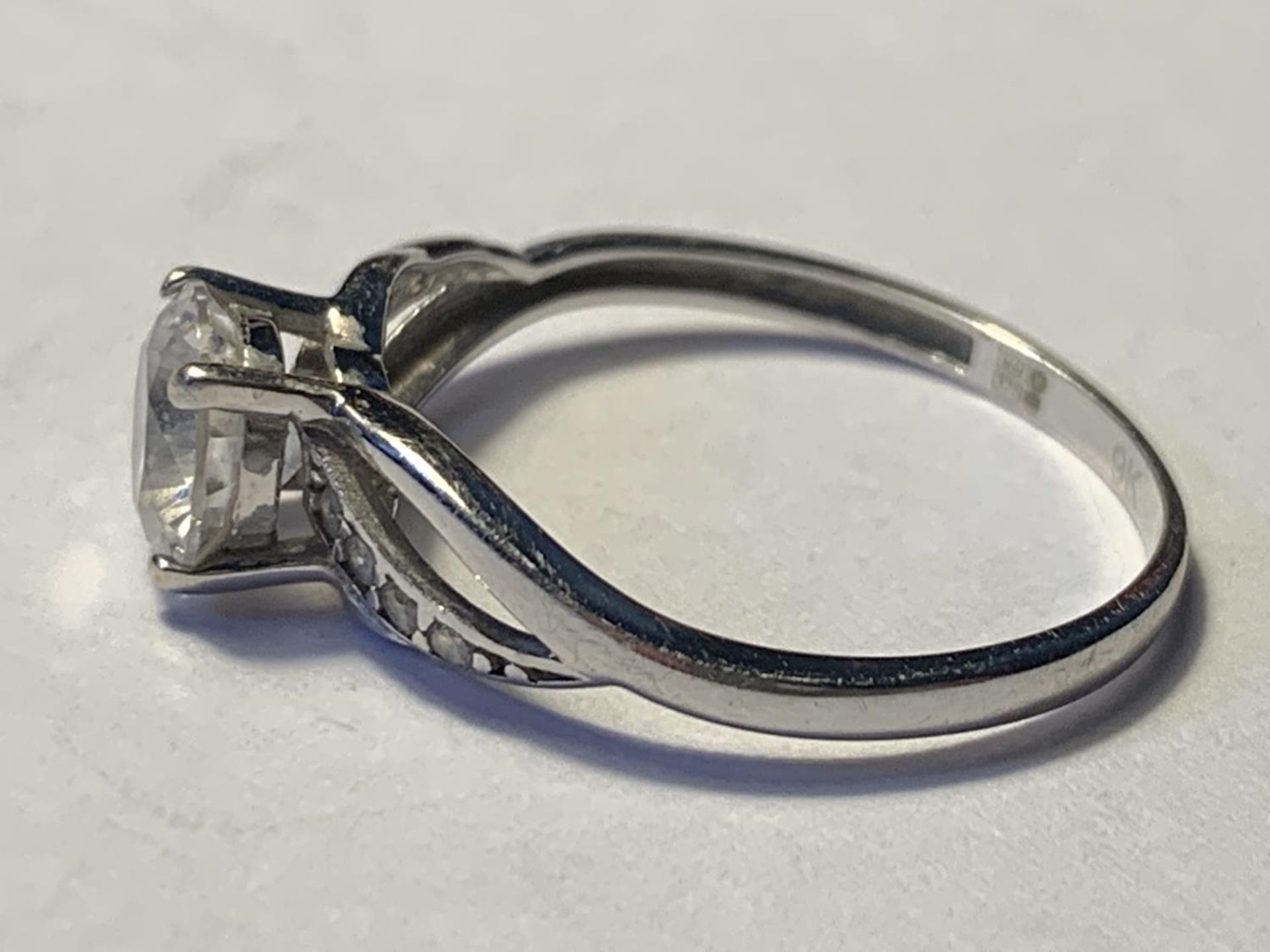 A 9 CARAT WHITE GOLD RING WITH A WITH A LARGE CENTRE CUBIC ZIRCONIA AND SMALLER TO THE SHOULDERS - Image 2 of 3