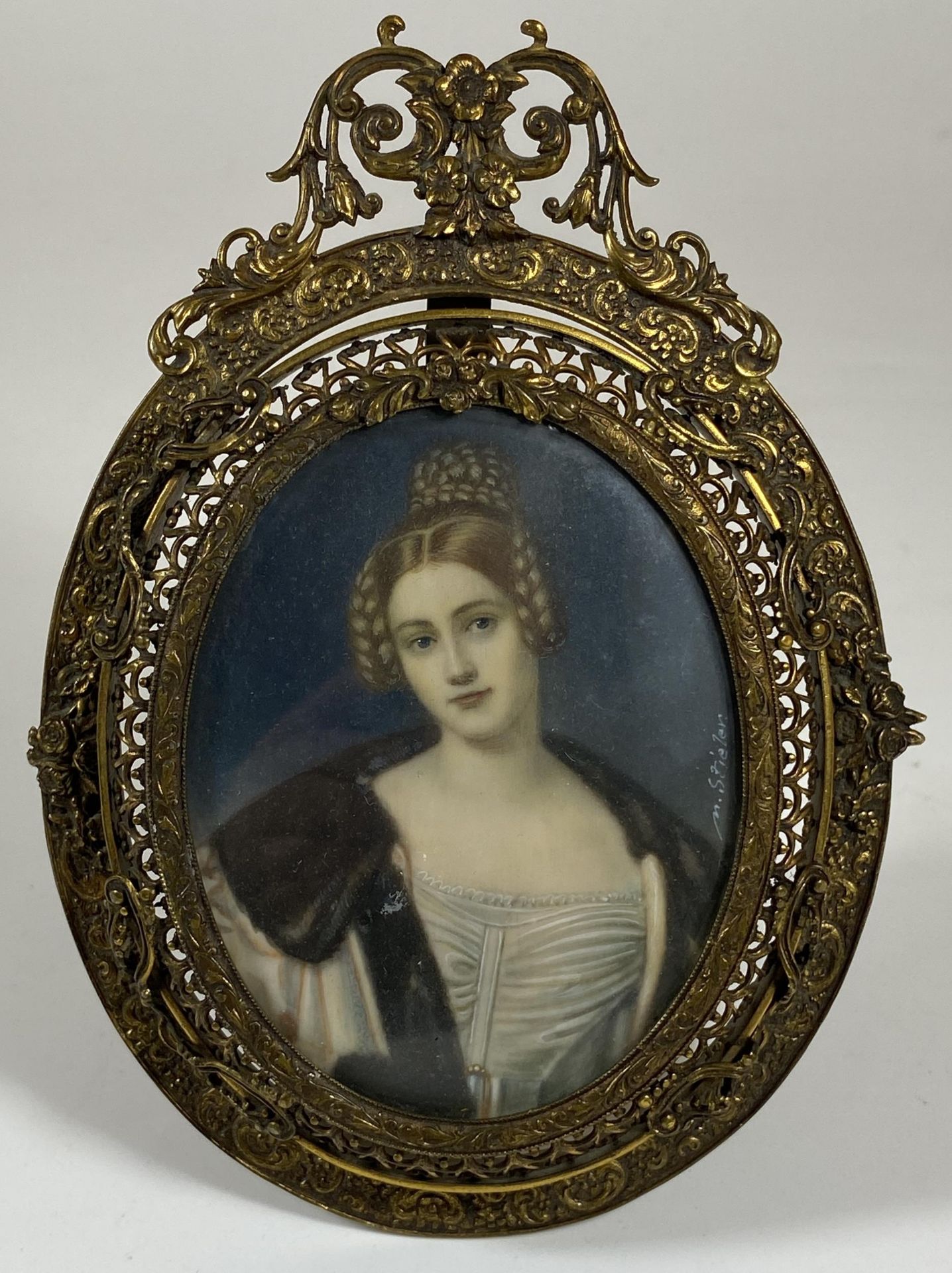 AN EARLY 19TH CENTURY HAND PAINTED PORTRAIT OF A LADY, SIGNED M.STIELER, IN ORNATE BRASS OVAL