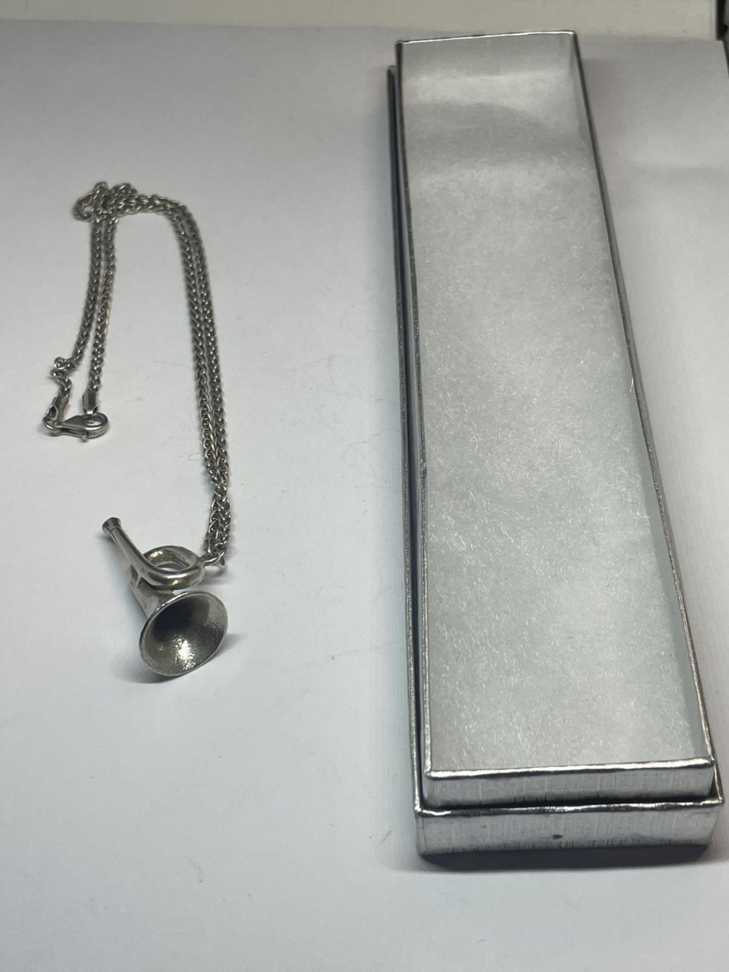 A SILVER NECKLACE WITH TRUMPET PENDANT IN A PRESENTATION BOX