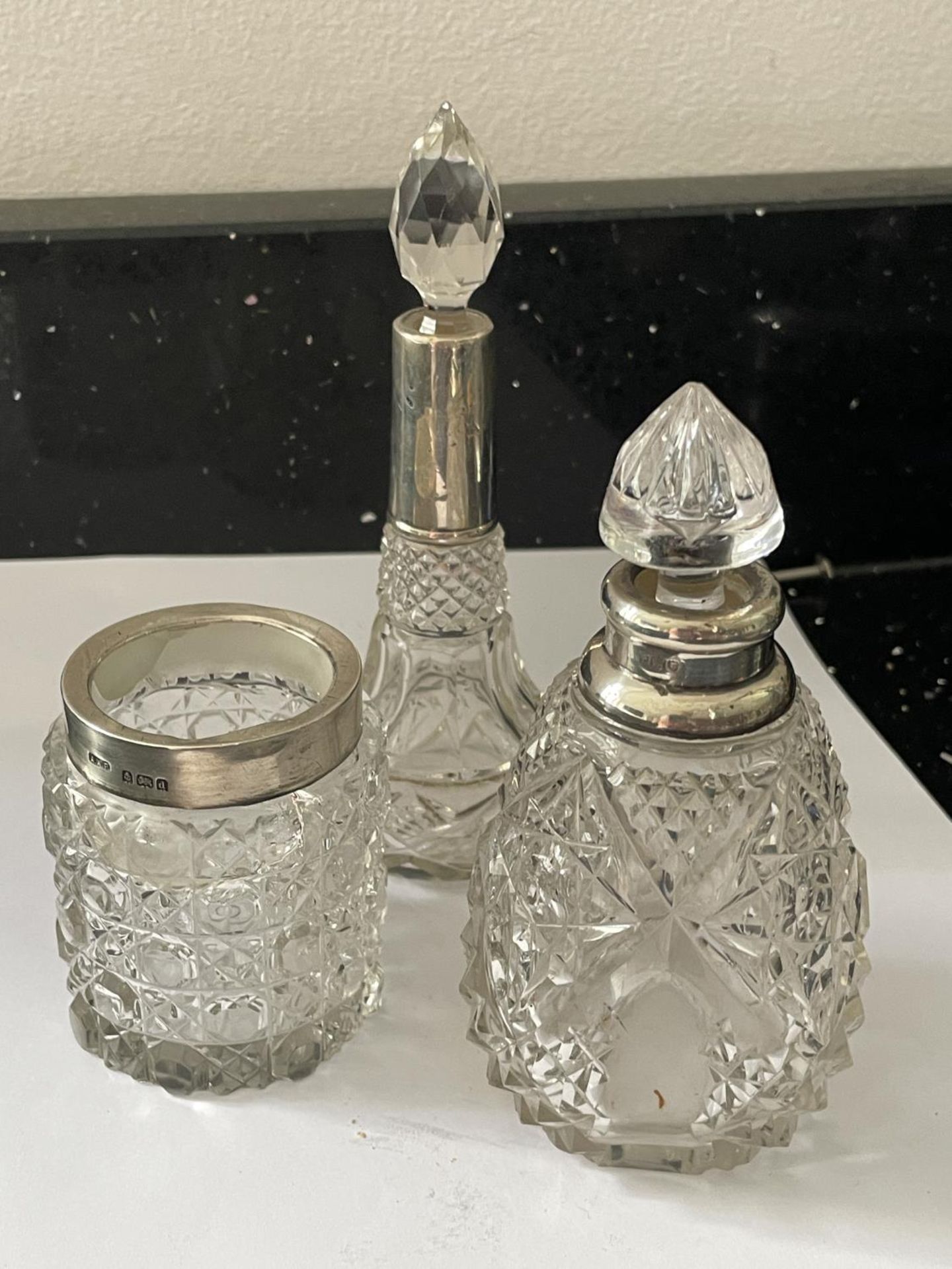 THREE CUT GLASS ITEMS TO INCLUDE A JAR WITH A HALLMARKED BIRMINGHAM COLLAR, A BOTTTLE WITH A