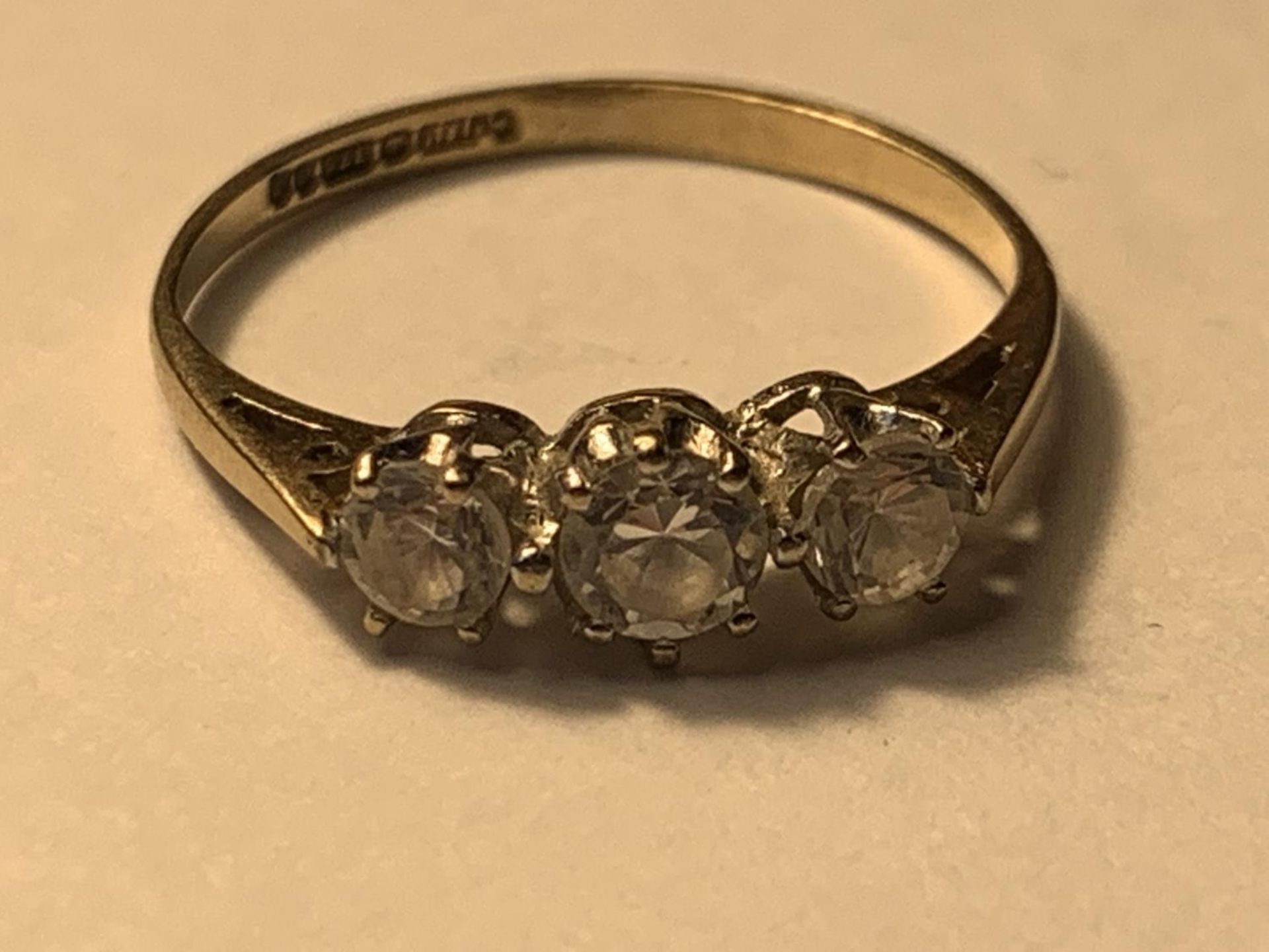 A 9 CART GOLD RING WITH THREE IN LINE CUBIC ZIRCONIAS SIZE K