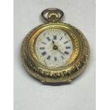 AN ORNATE 18 CARAT GOLD FOB WATCH WITH WHITE ENAMAL FACE AND ROMAN NUMERALS WITH FLOWER DESIGN TO