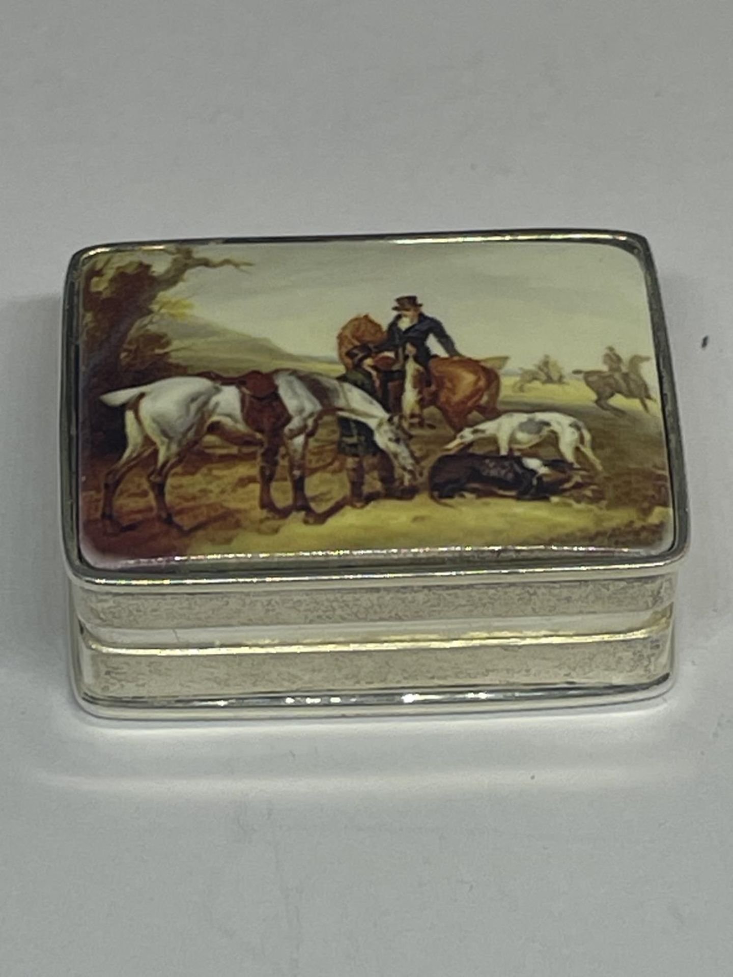 A SILVER PILL BOX WITH AN ENAMELLED HUNTING DESIGN LID