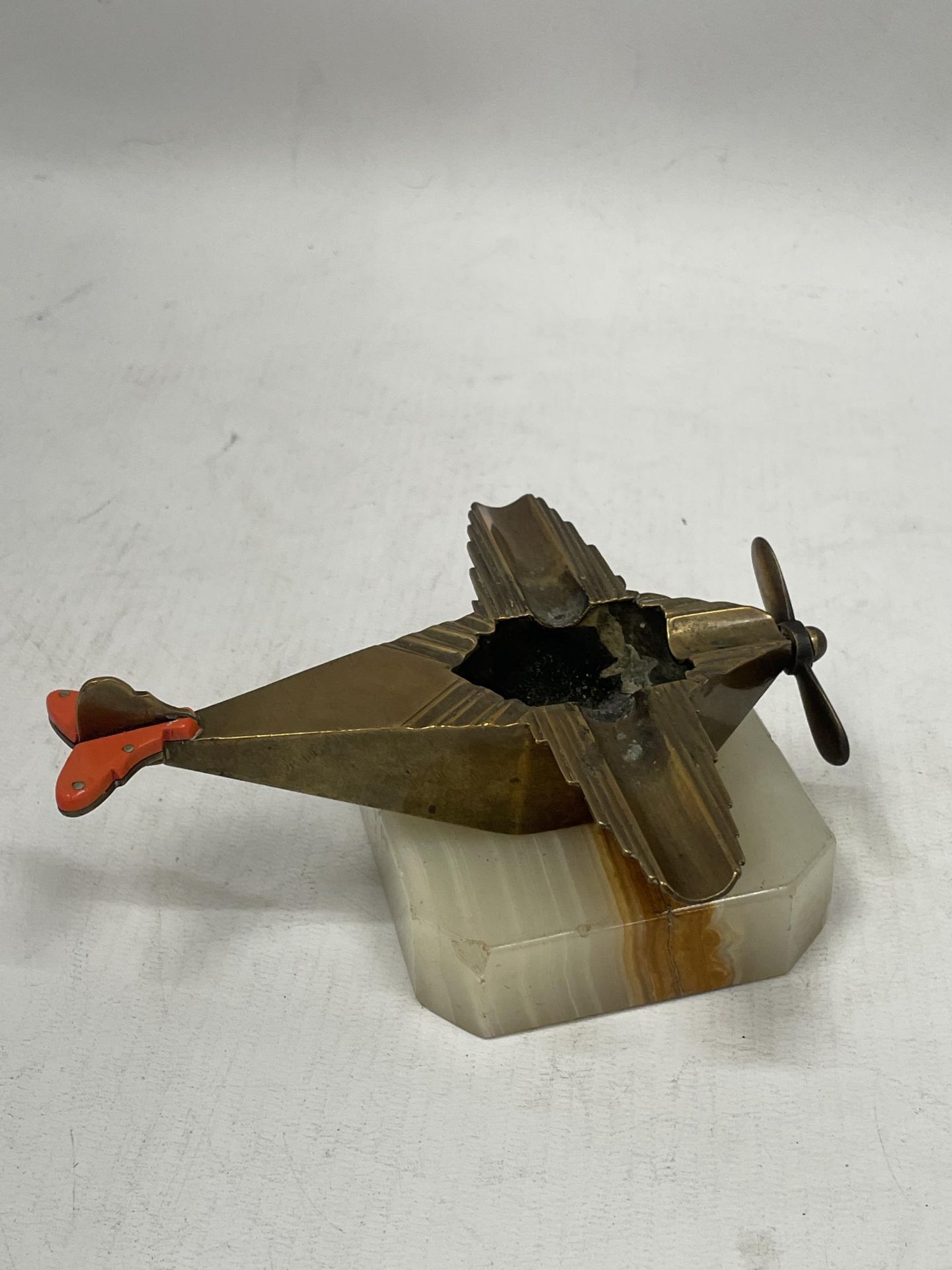 A VINTAGE ART DECO BRASS AEROPLANE ASHTRAY ON ONYX STAND