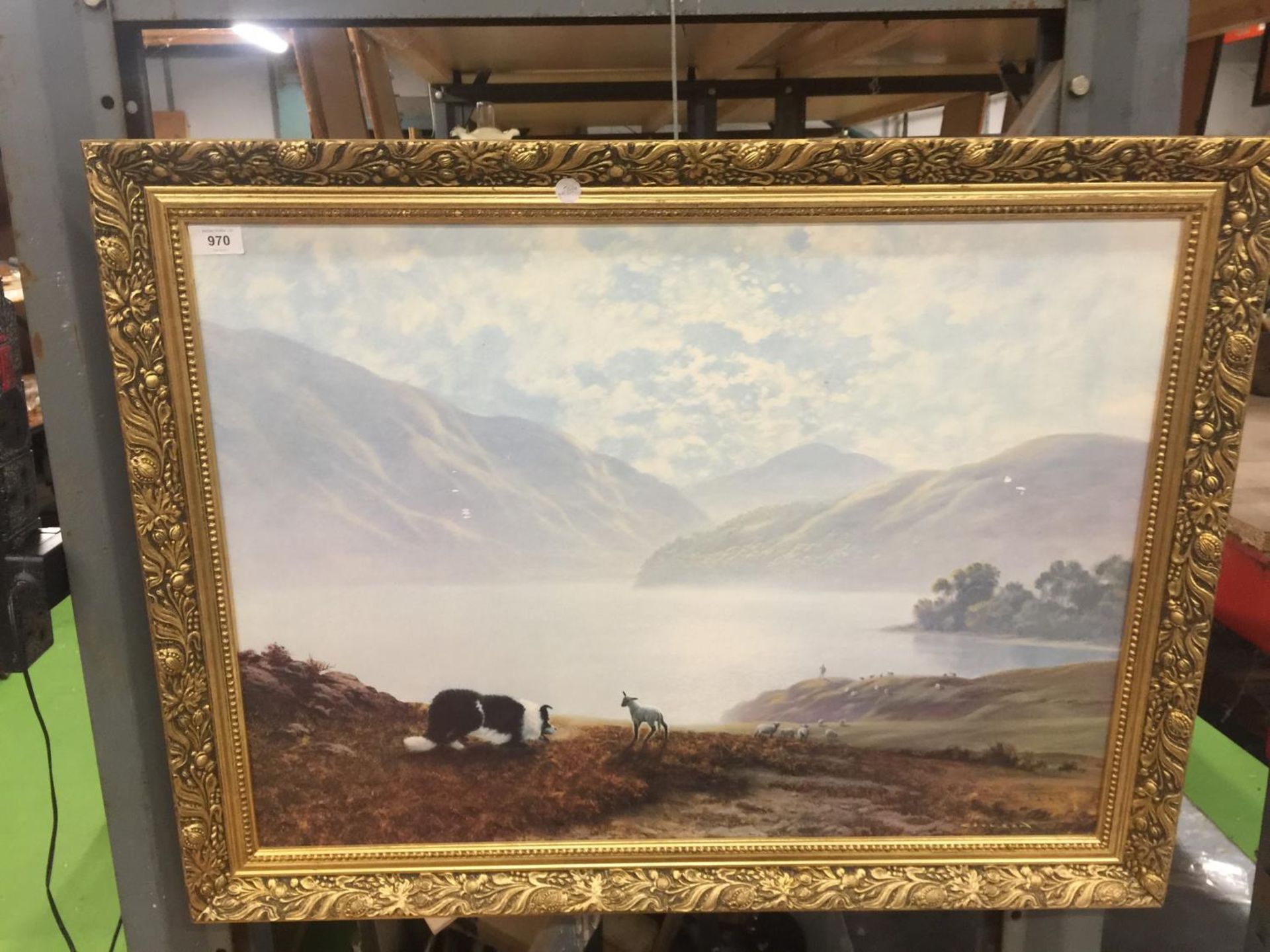 A LARGE GILT FRAMED PRINT OF A SHEEPDOG ROUNDING UP SHEEP IN A LAKELAND SETTING