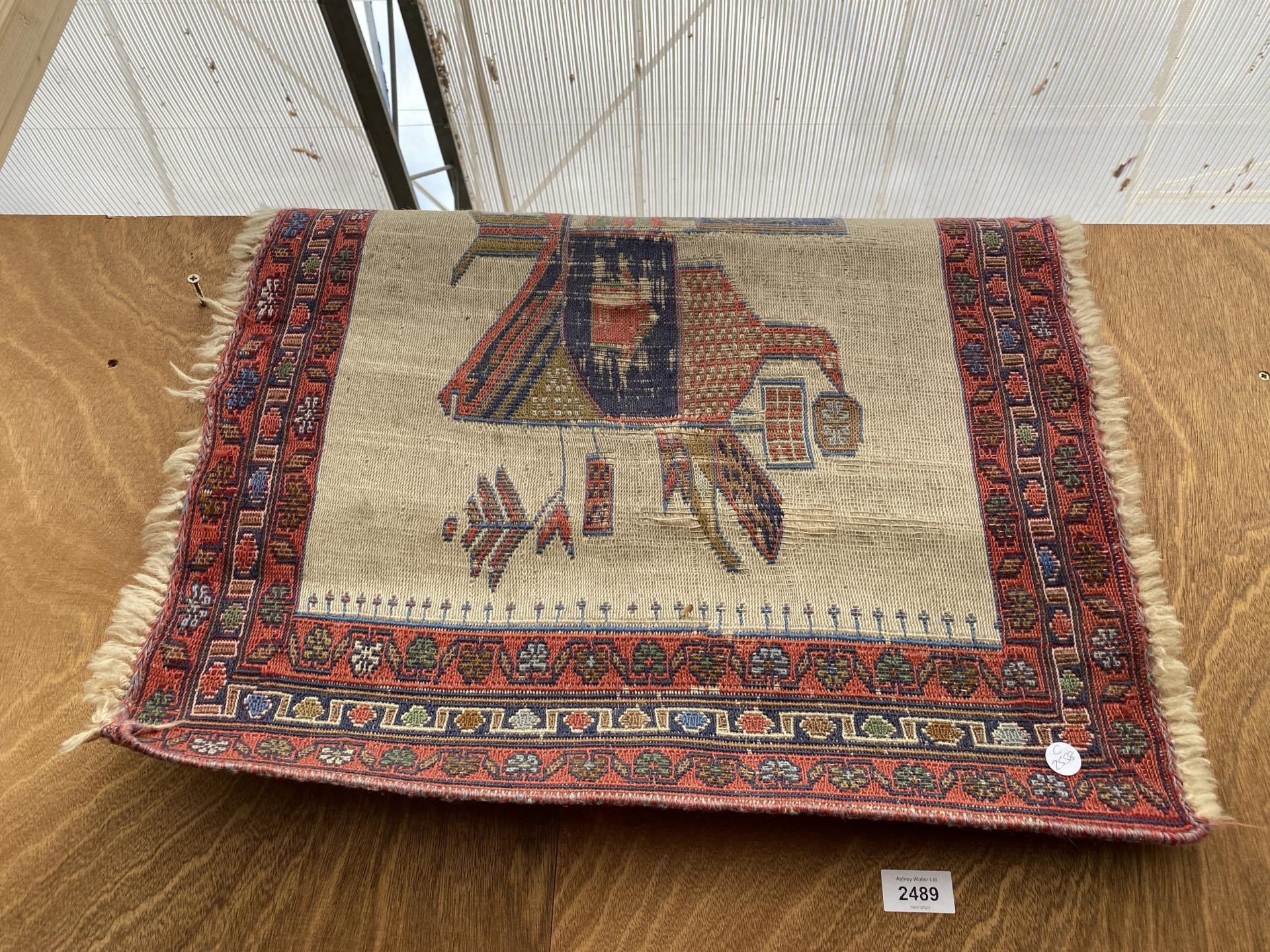 A SMALL RED PATTERNED FRINGED RUG