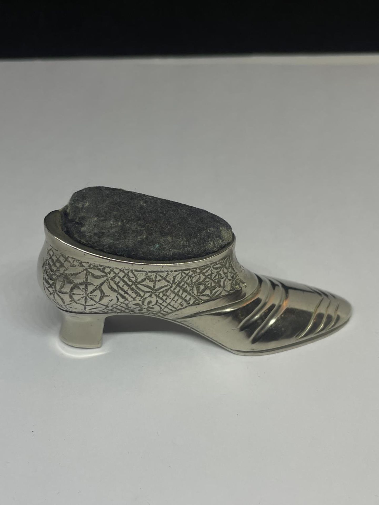 A WHITE METAL SHOE DESIGN PIN CUSHION