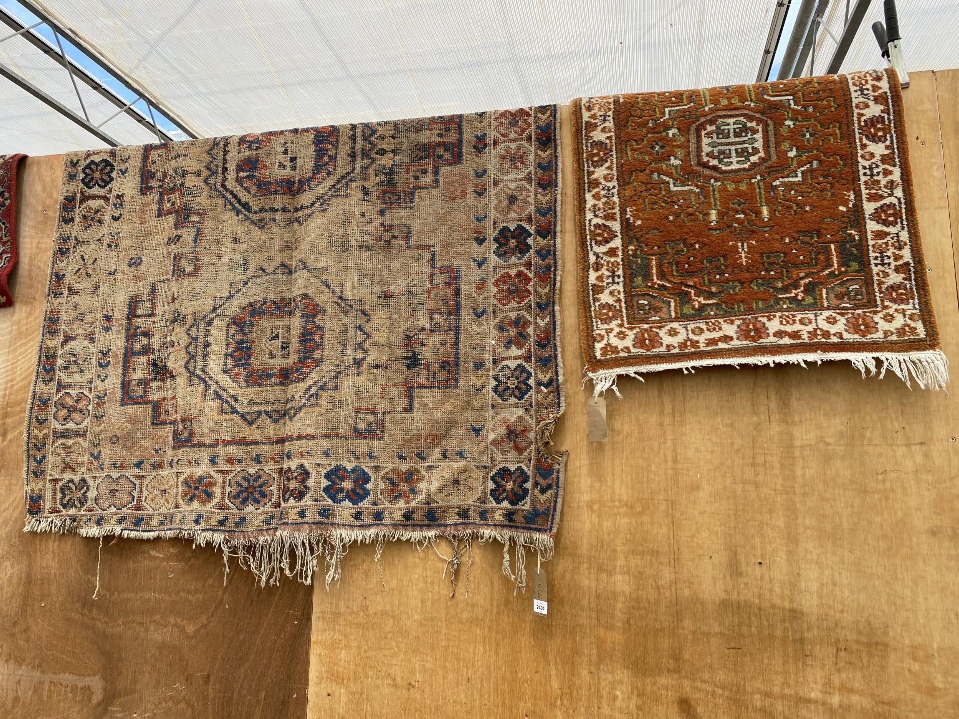 A VINTAGE FRINGED PATTERNED RUG AND A SMALL ORANGE PATTERNED FRINGED RUG