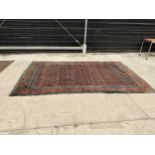 AN ANTIQUE, BELIEVED PERSIAN RUG 206 CM X 133 CM - HAS A TEAR, SEE PHOTOS 2 AND 6