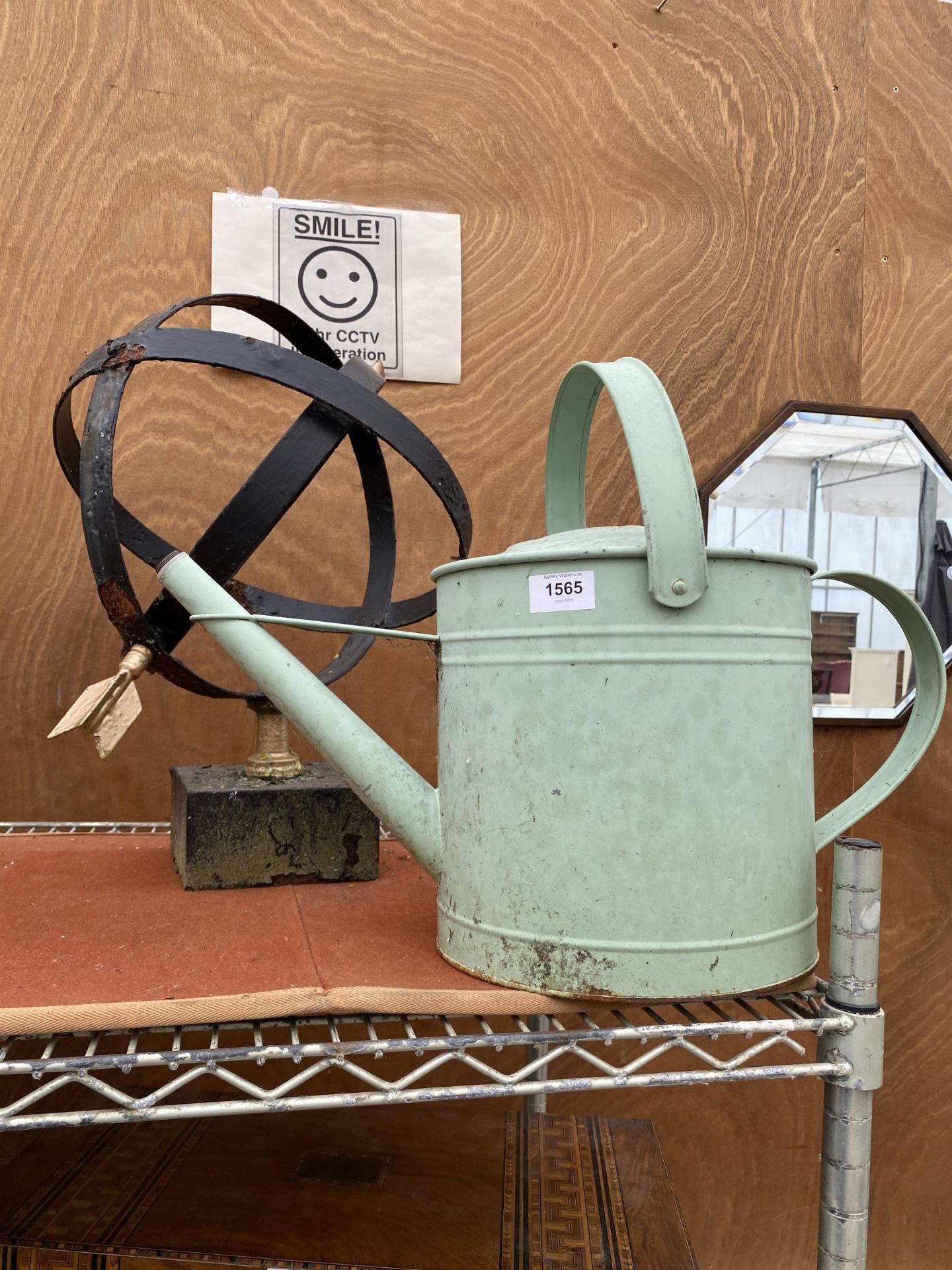 A PAINTED METAL WATERING CAN AND AN ARMILARY SPHERE