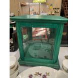 A GREEN WOODEN DISPLAY CABINET WITH A GLASS SHELF