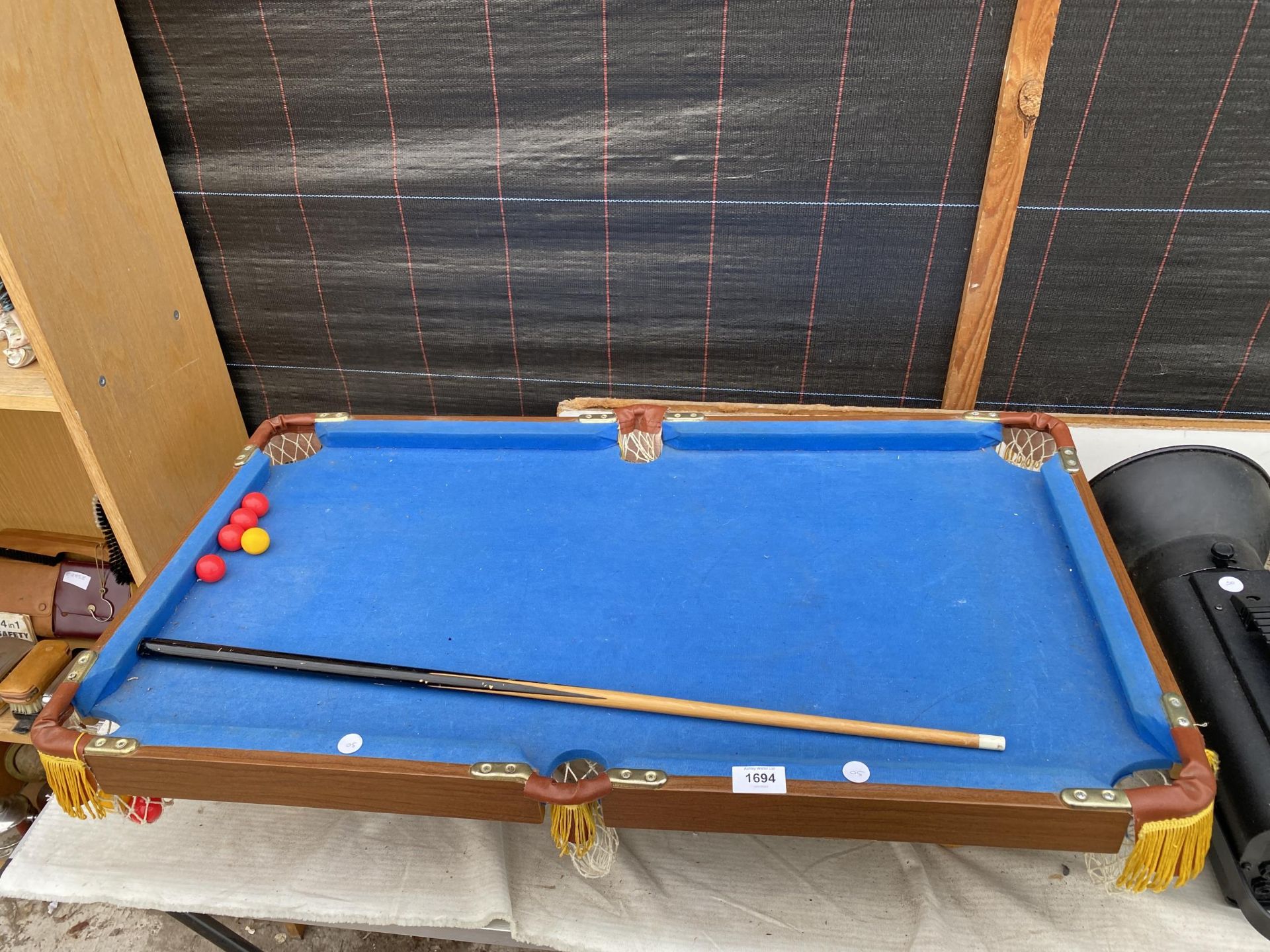 A TABLE TOP POOL TABLE WITH CUE AND BALLS