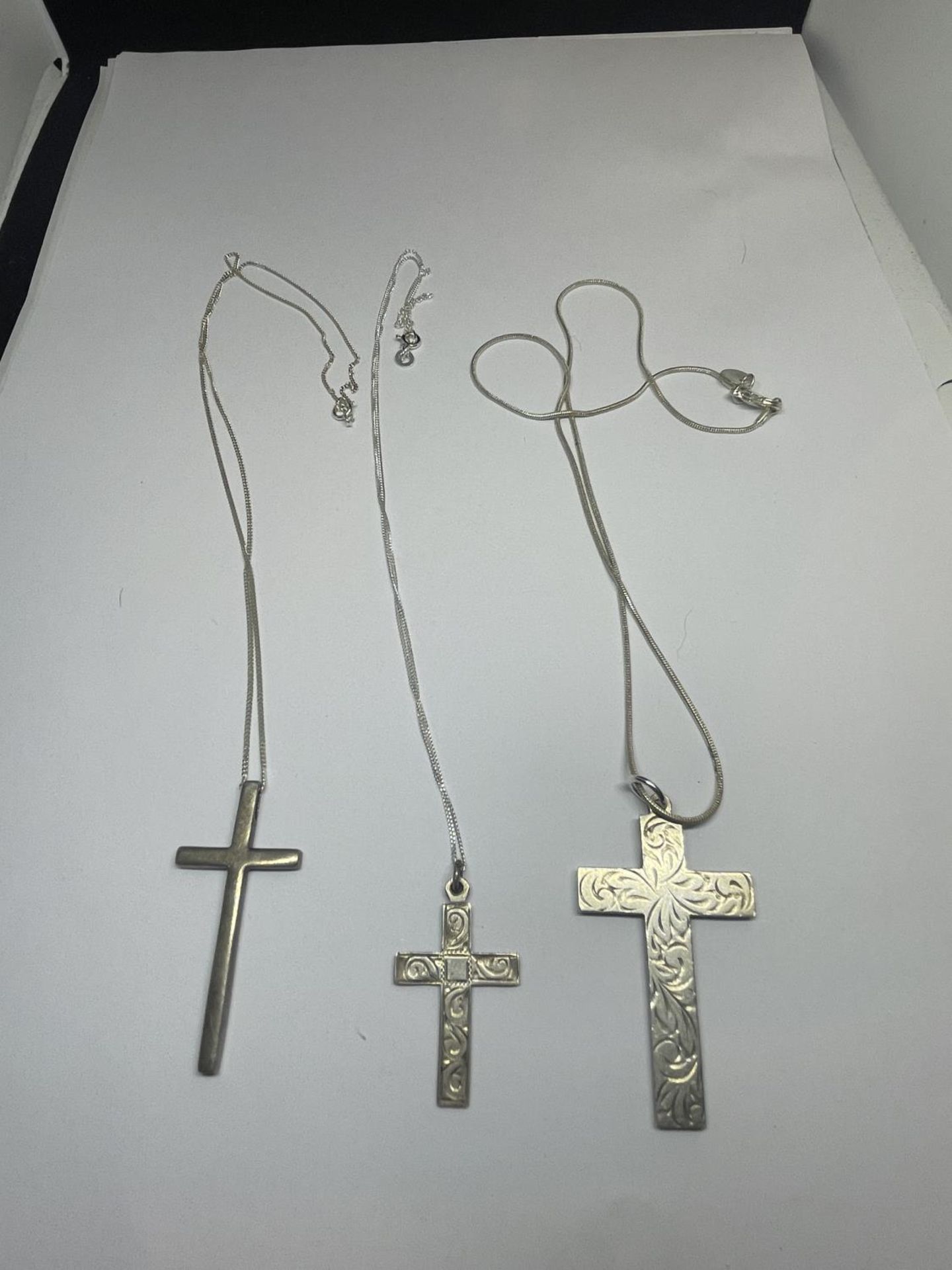 THREE SILVER NECKLACES WITH CROSS PENDANTS