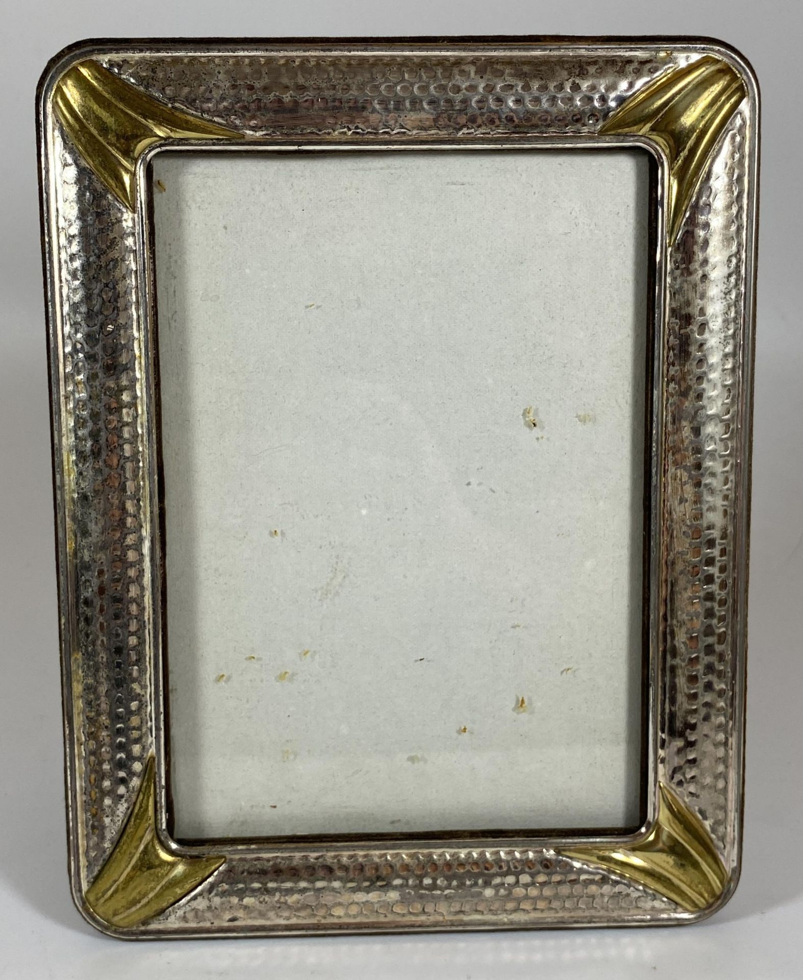 A VINTAGE HAMMERED WHITE METAL PHOTO FRAME, POSSIBLY SILVER BUT UNMARKED, 22 X 17CM