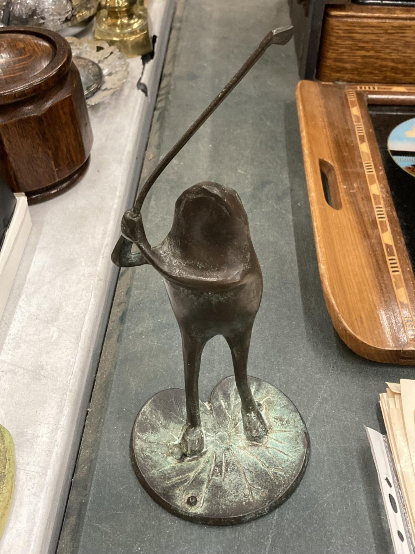 A BRONZE STYLE FROG PLAYING GOLF ON A LILY PAD, HEIGHT 25CM