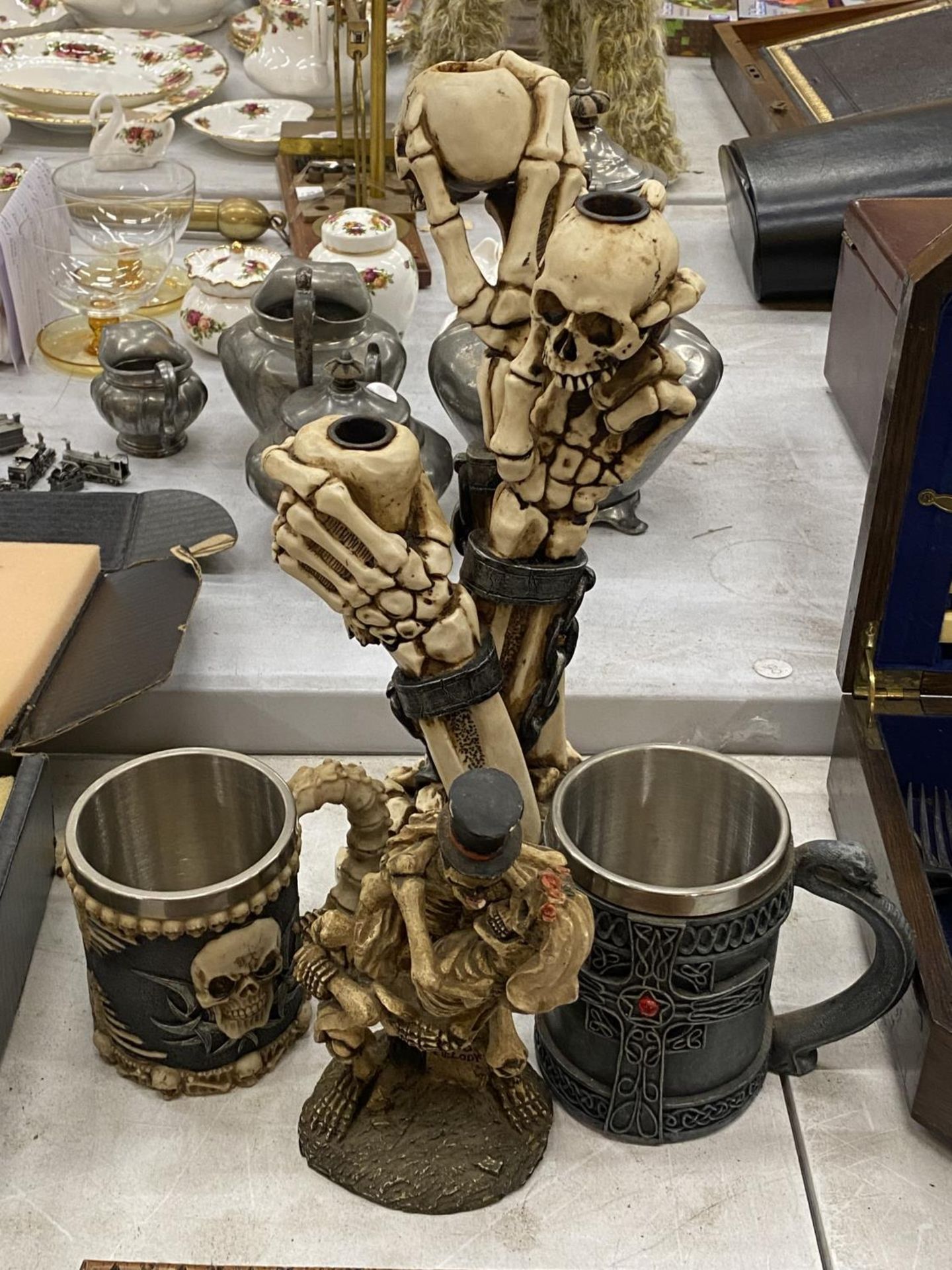 A RESIN SKELETON CANDLESTICK HEIGHT 34CM, A SKELETON BRIDE AND GROOM AND TWO TANKARDS