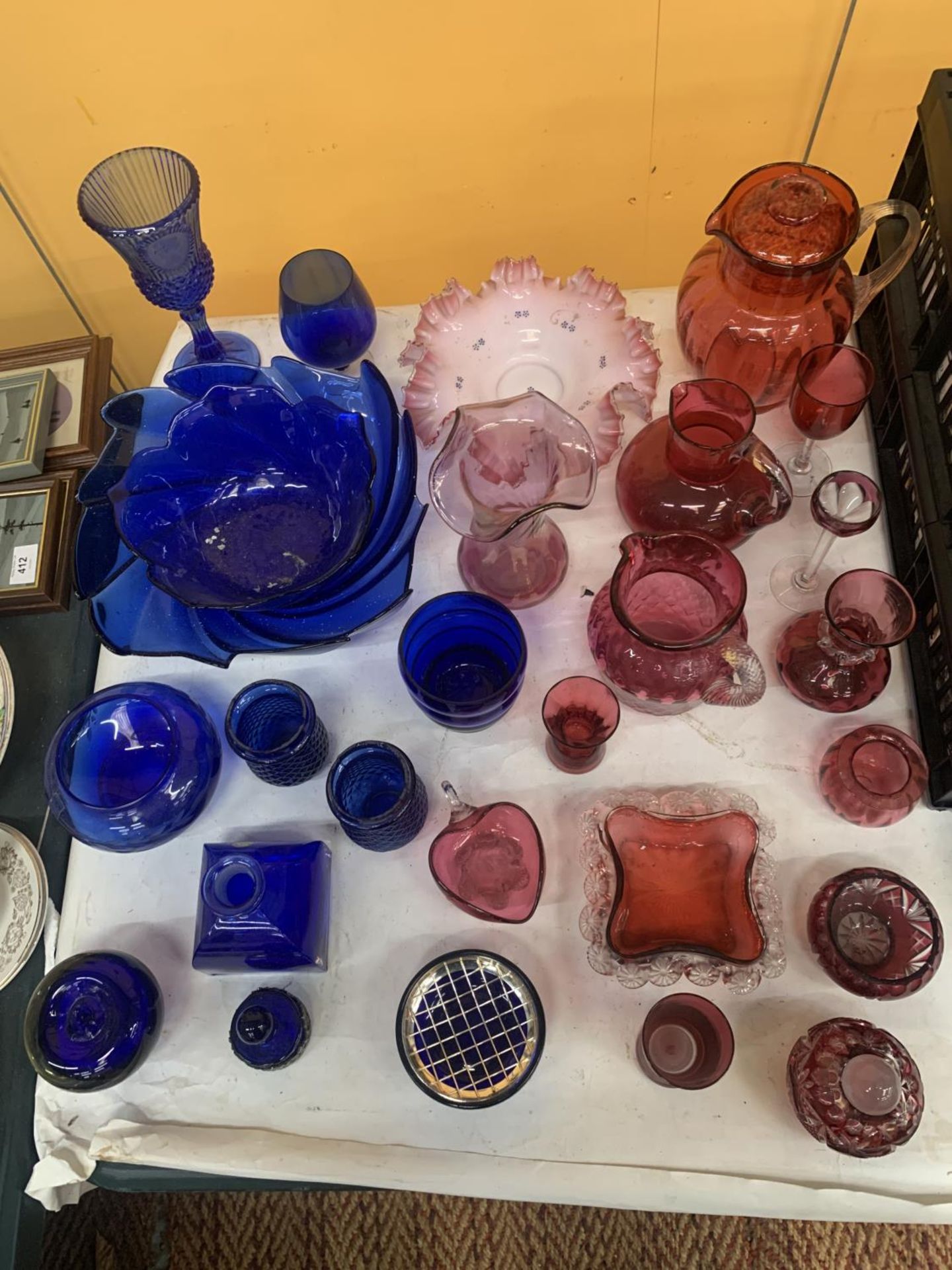 A LARGE QUANTITY OF VINTAGE CRANBERRY AND BLUE GLASS TO INCLUDE BOWLS, VASES, JUGS, ETC