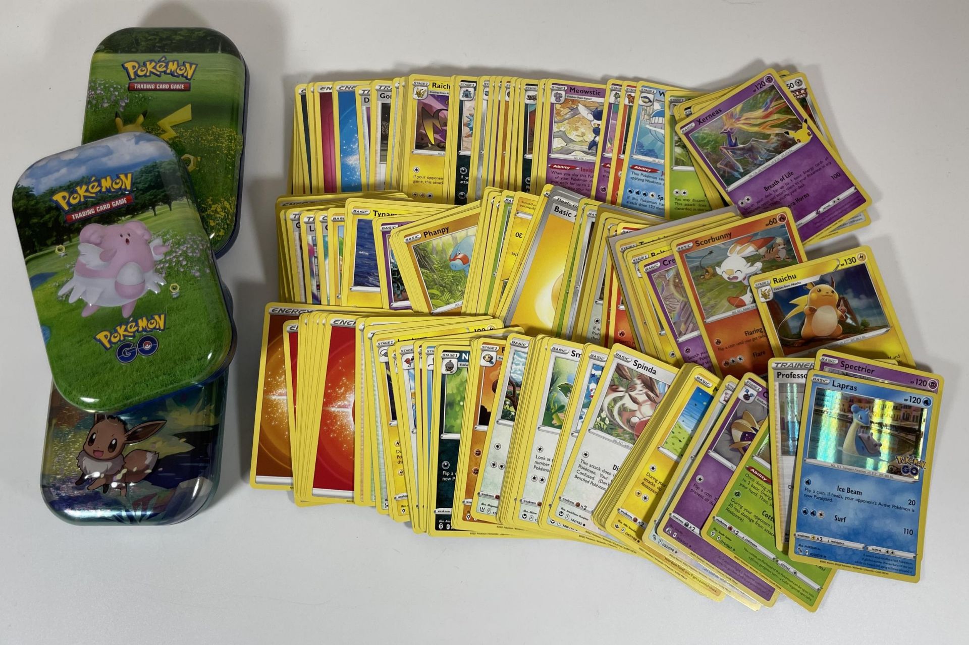 THREE TINS OF ASSORTED POKEMON TRADING CARDS, HOLOS ETC