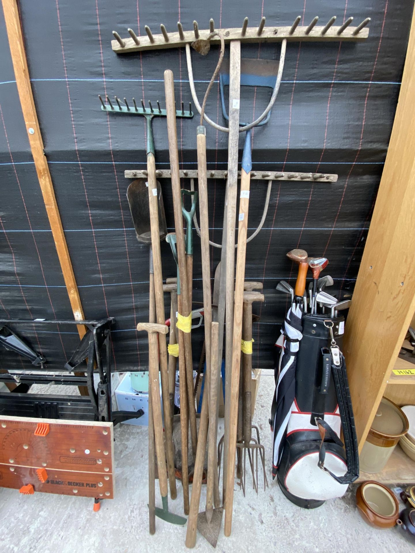 AN ASSORTMENT OF GARDEN TOOLS TO INCLUDE RAKES, FORKS AND SPADES ETC