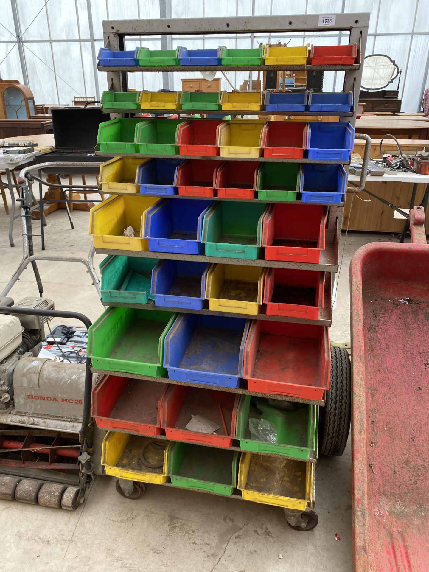 A FOUR WHEELED TROLLEY WITH A LARGE QUANTITY OF PLASTIC LIN BINS