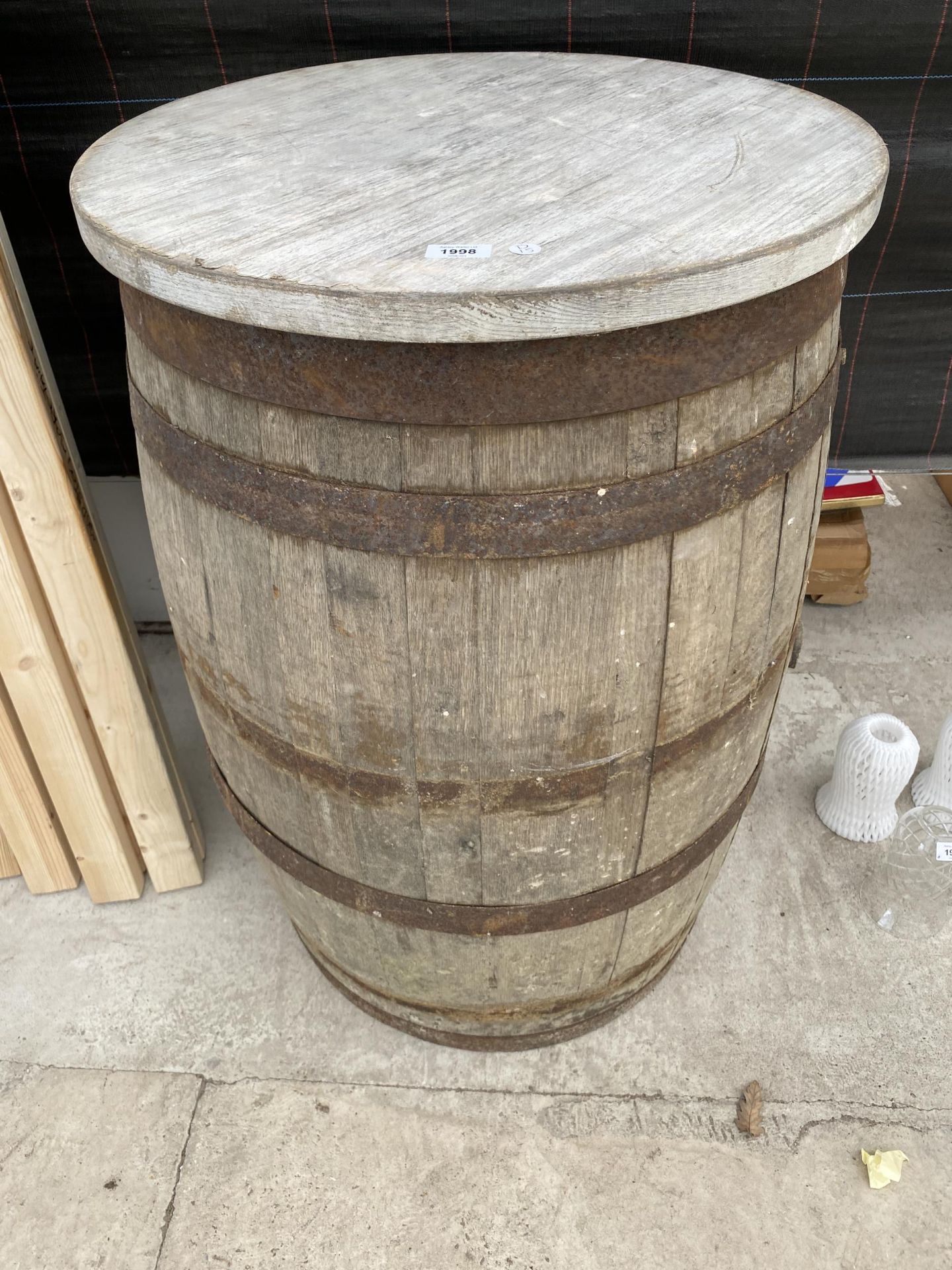 A METAL BANDED OAK WHISKEY BARREL WITH ROUND TIMBER TOP