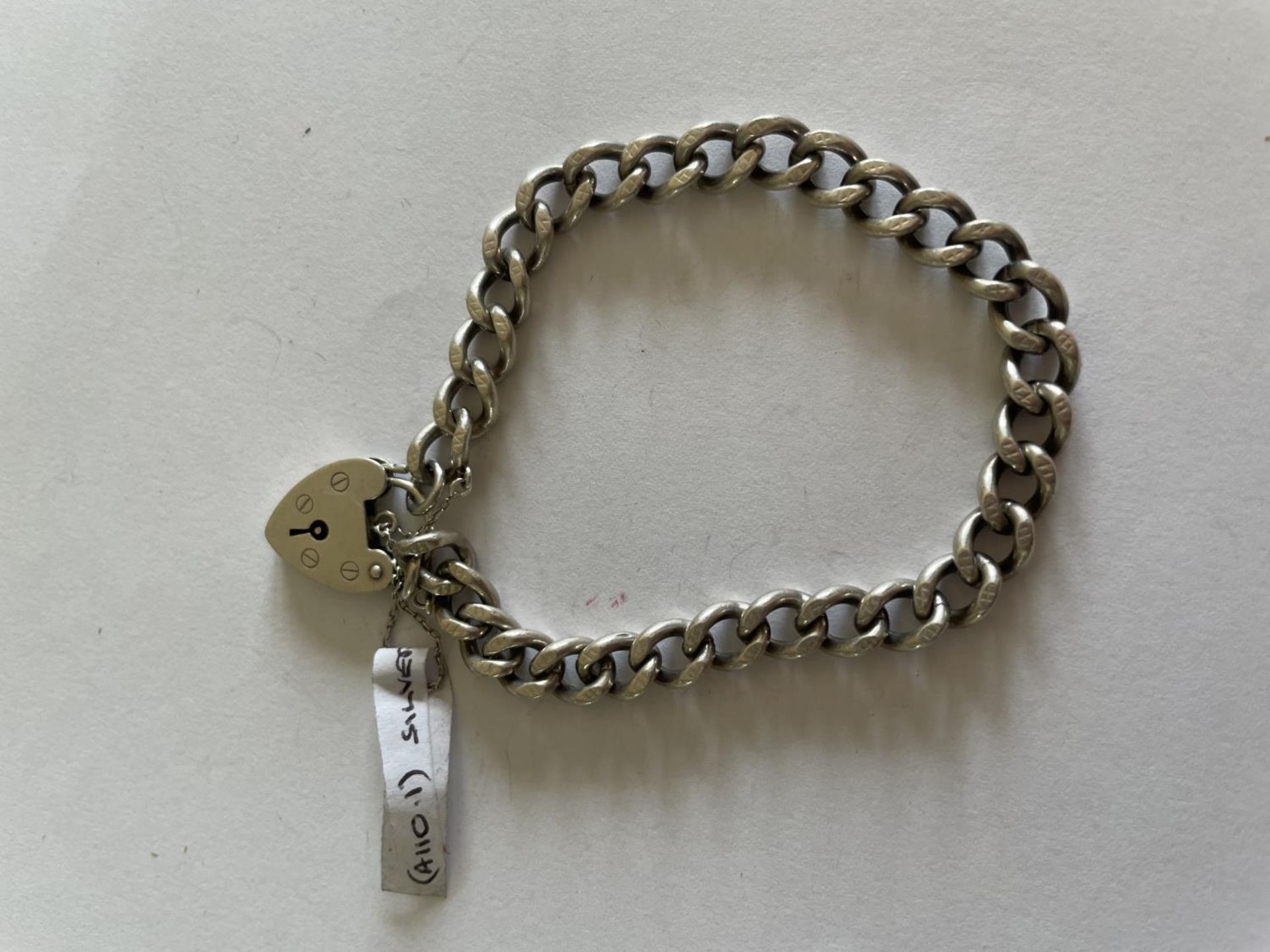 A HEAVY SILVER BRACELET WITH A HEART PADLOCK