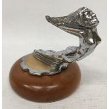 A NUDE LADY CHROME EFFECT CAR MASCOT ON WOODEN BASE