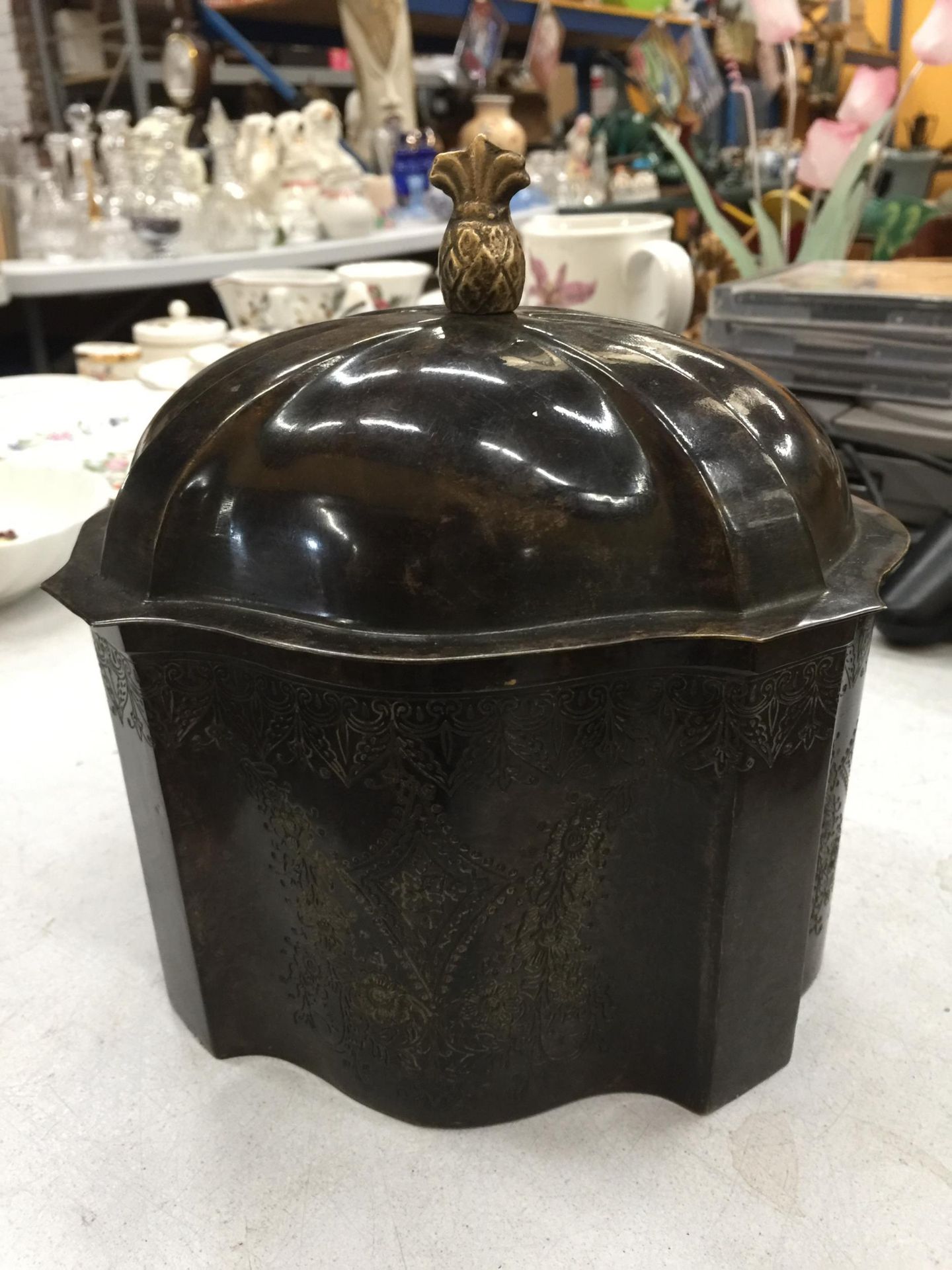 A VINTAGE METAL TEA CADDY WITH FOLIATE ETCHING TO THE BASE AND A PINEAPPLE FINIAL