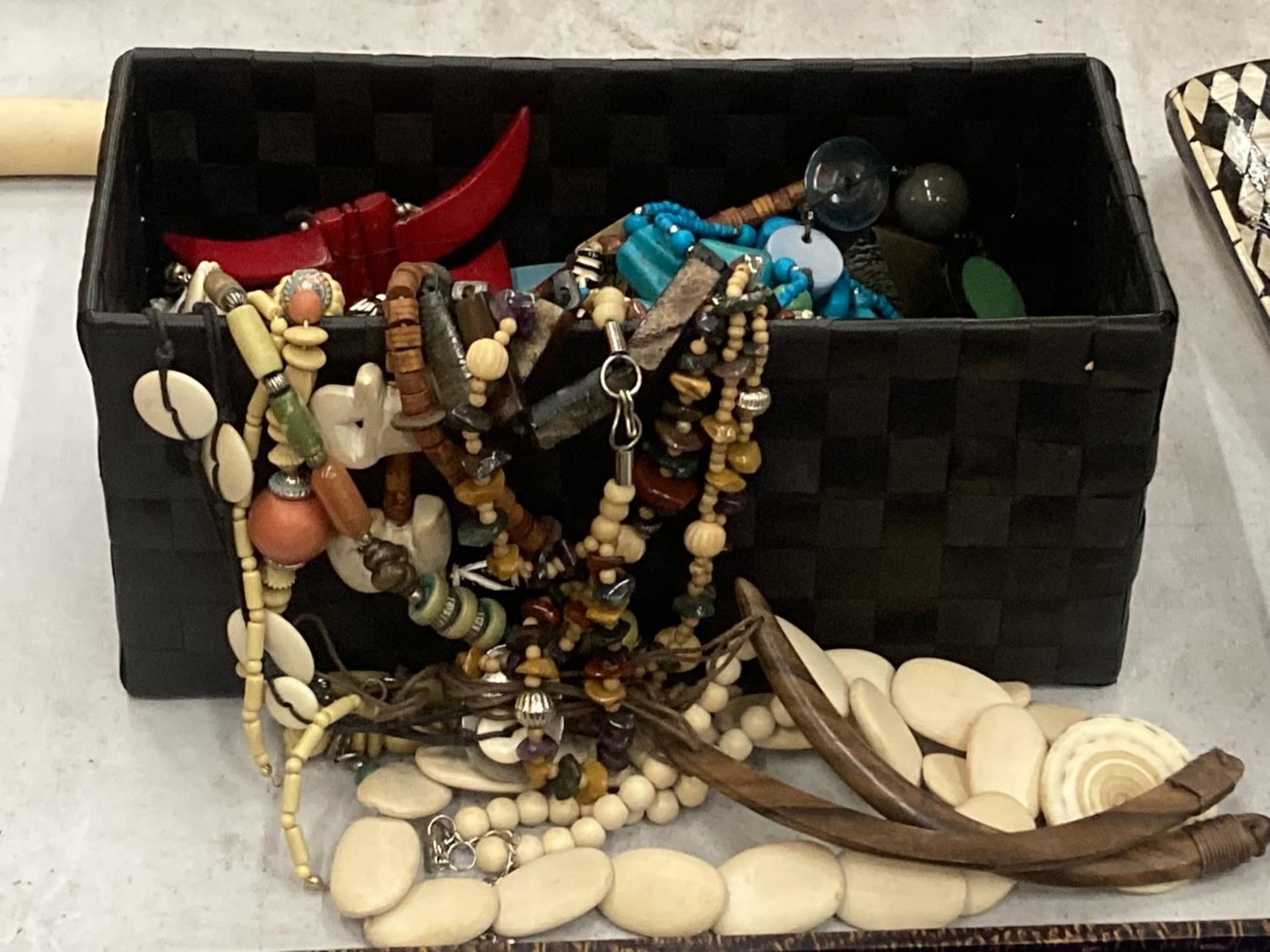 A QUANTITY OF COSTUME JEWELLERY IN A BLACK BASKET