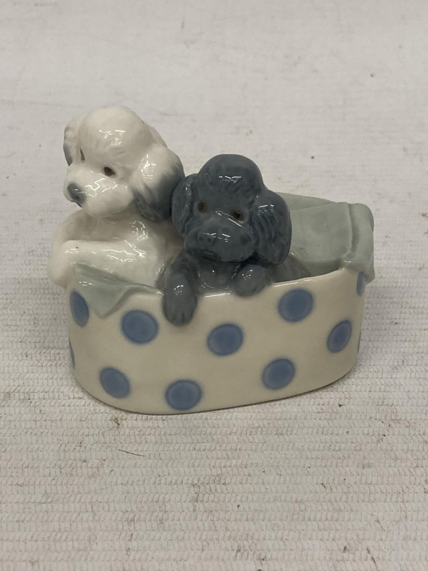 A NAO FIGURE OF TWO DOGS IN A BASKET