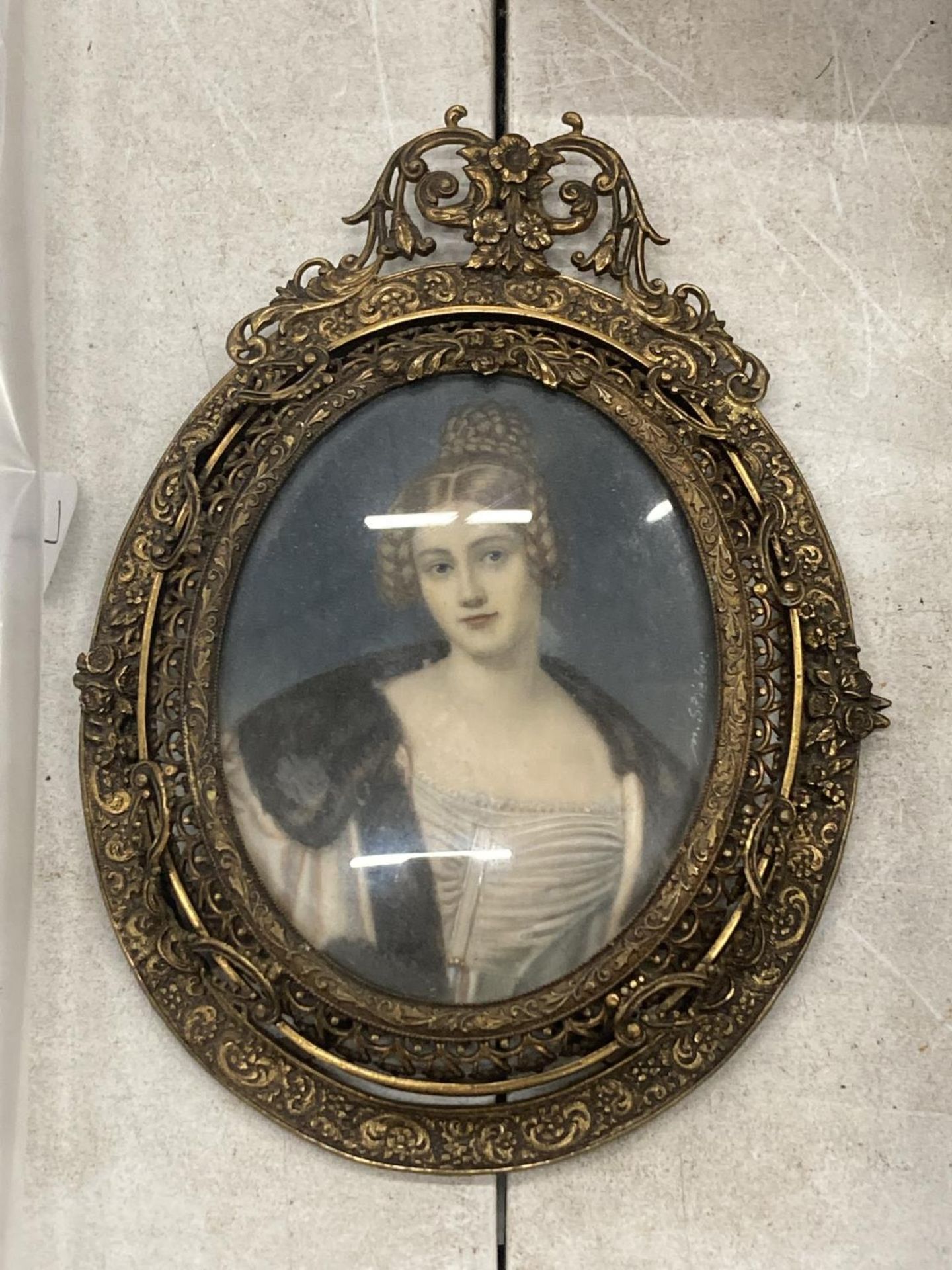 AN EARLY 19TH CENTURY HAND PAINTED PORTRAIT OF A LADY, SIGNED M.STIELER, IN ORNATE BRASS OVAL