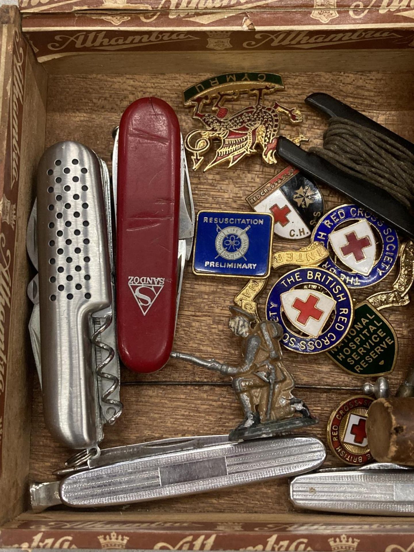 A CIGAR BOX CONTAINING VINTAGE PENKNIVES, RED CROSS BADGES, A BOTTLE STOPPER WITH WHITE METAL DUCK - Image 2 of 4